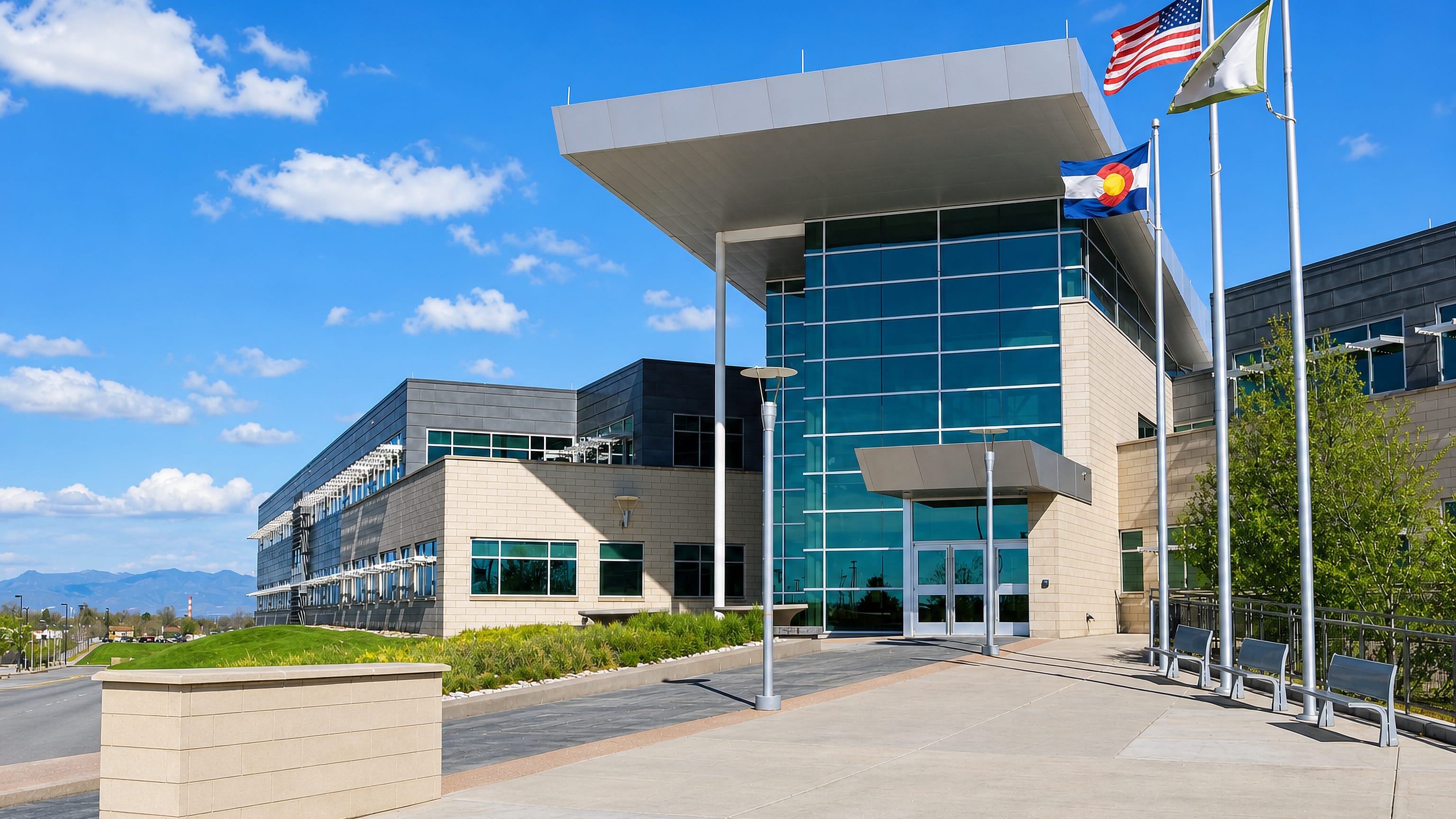 Glass-fronted civic center building flying US, Colorado and city flags in Commerce City, Colorado.