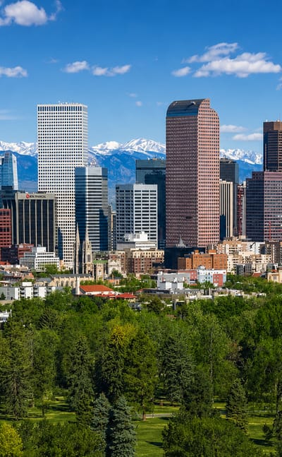 Denver's downtown skyline with the Rocky Mountains behind and a green park in the foreground.