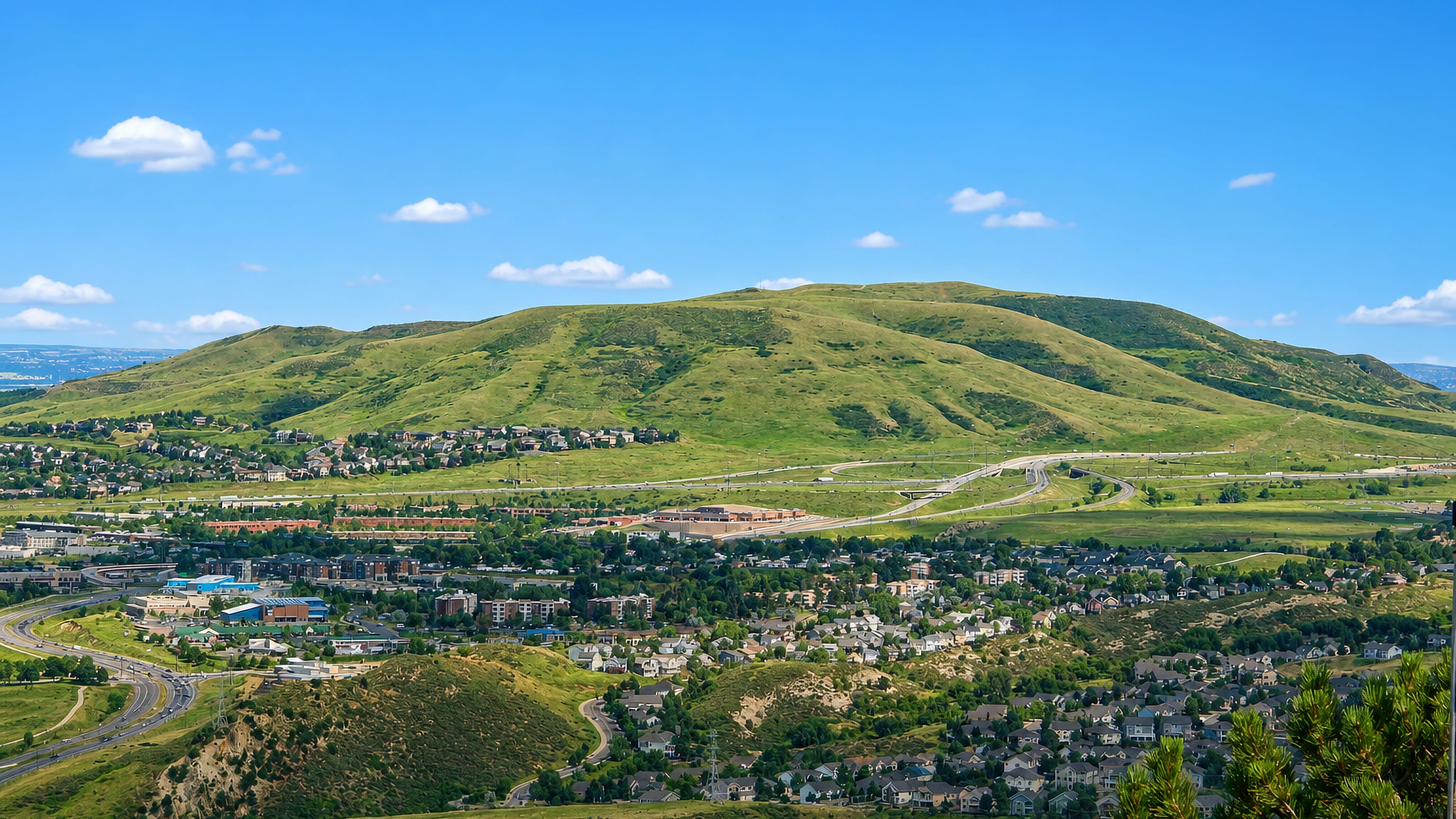 Lakewood, Colorado, spread below the grassy slopes of Green Mountain with highway interchanges.
