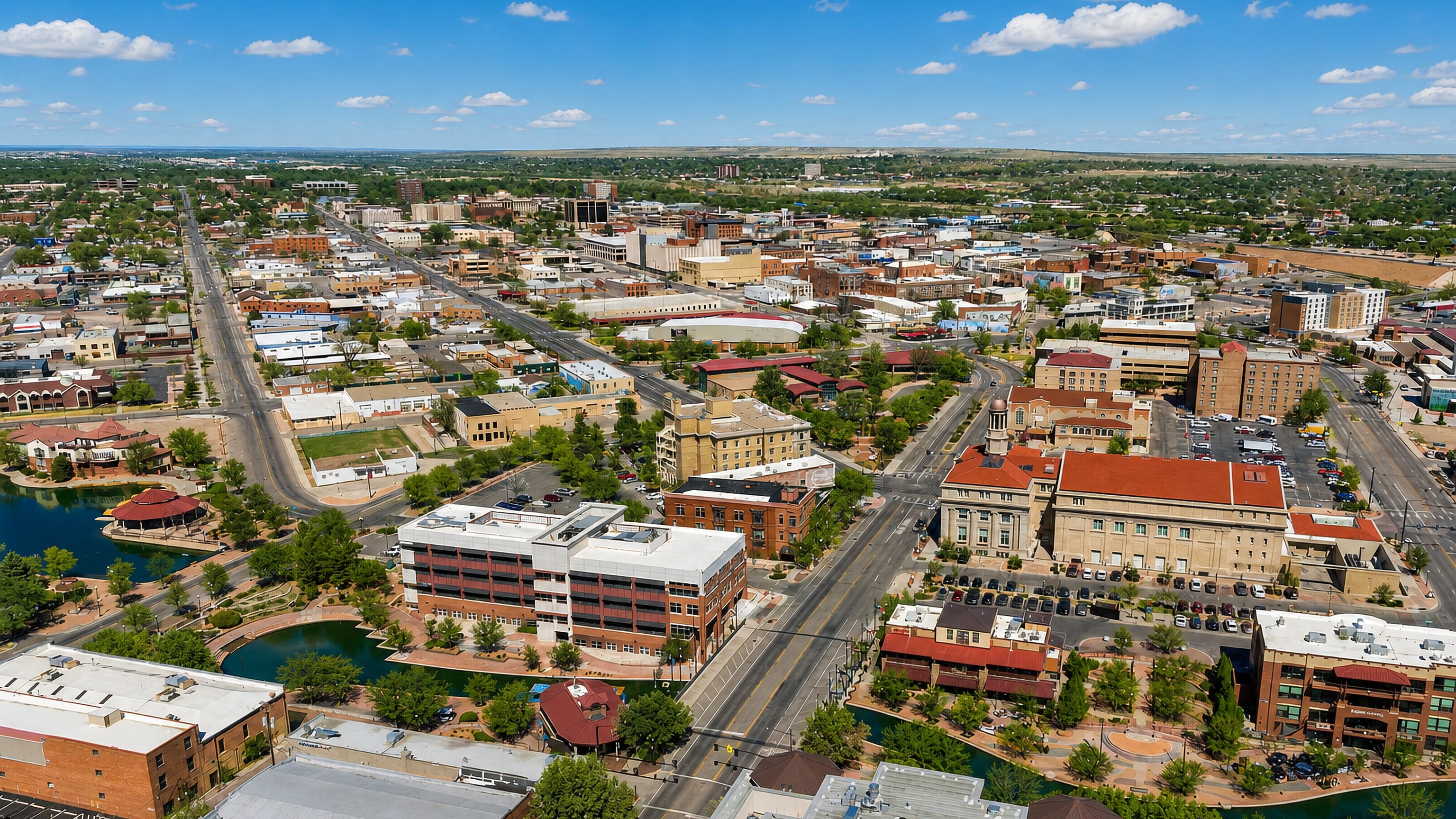 Aerial view of downtown Pueblo, Colorado, with the Riverwalk channels, historic brick blocks and plains beyond.