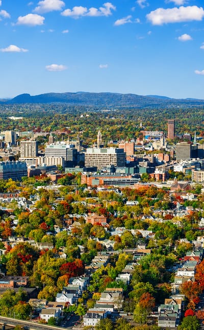 Aerial view of New Haven, Connecticut, downtown amid autumn foliage with traprock ridges in the distance.