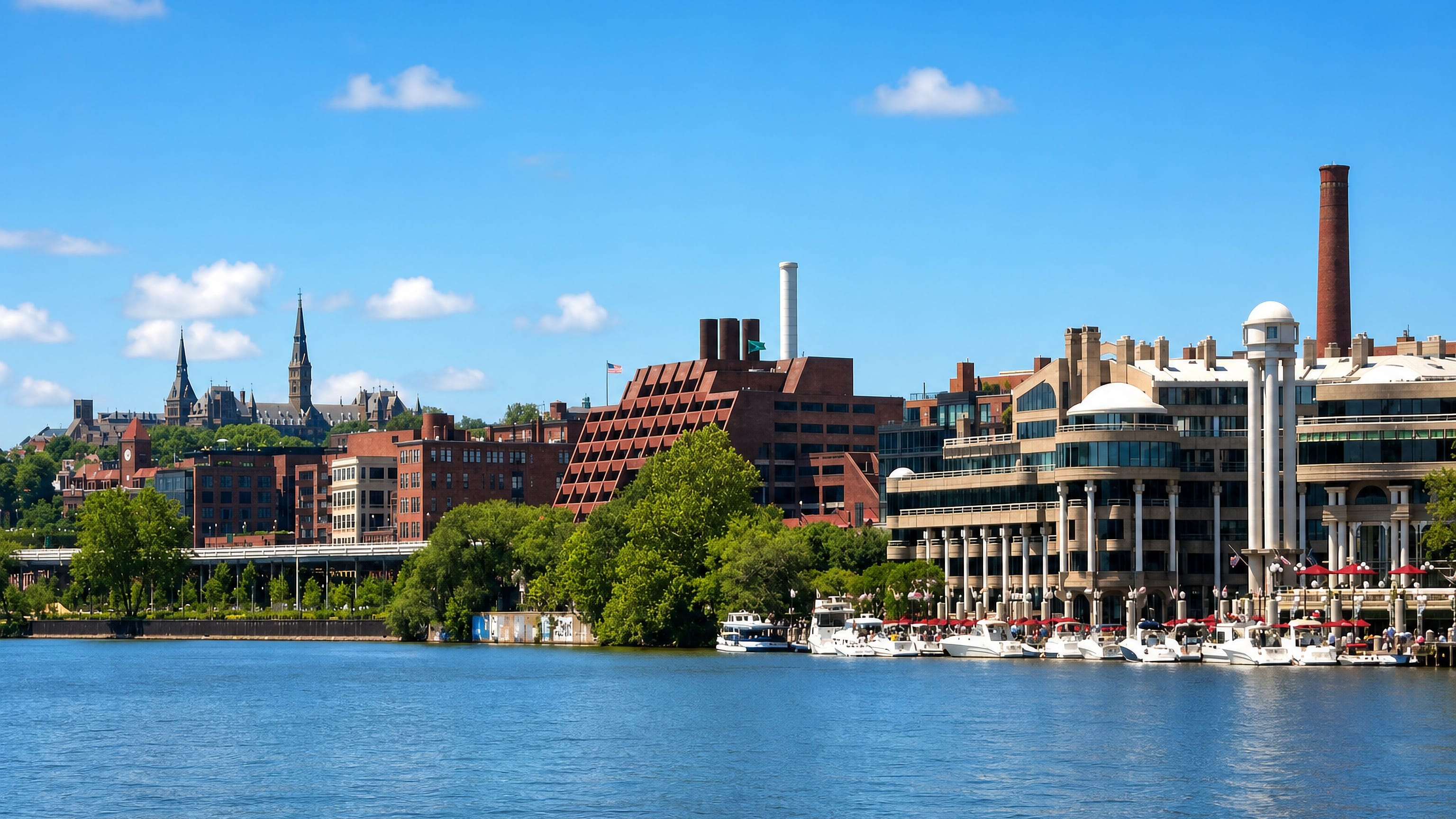 Georgetown's Potomac waterfront in Washington, DC, with Washington Harbour, moored boats and university spires.