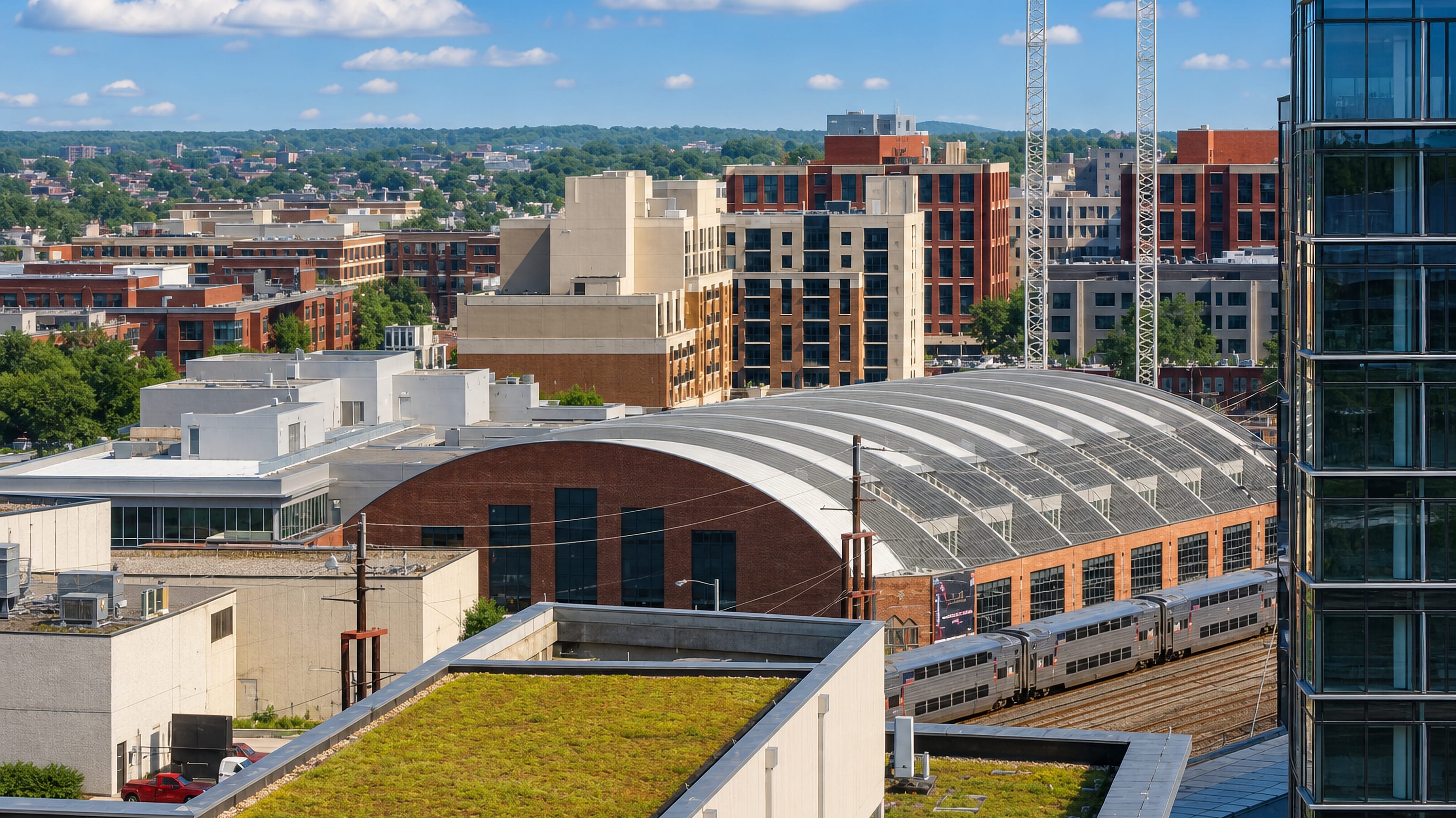 Rail yard, arched glass train shed and new mid-rise apartment blocks seen over rooftops in NoMa, Washington DC.