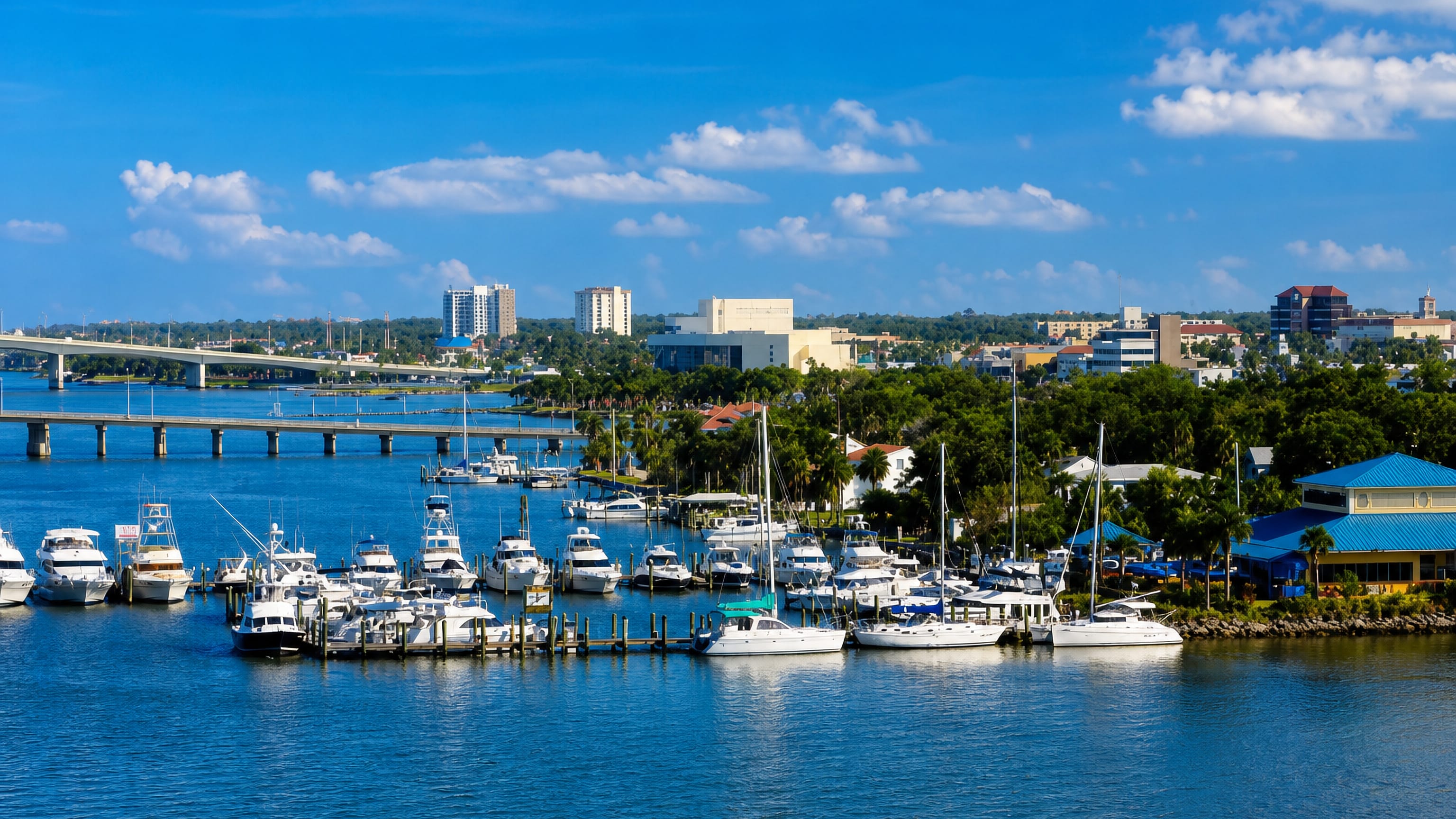 Daytona Beach marina on the Halifax River, with moored boats, a causeway bridge and the low downtown skyline.