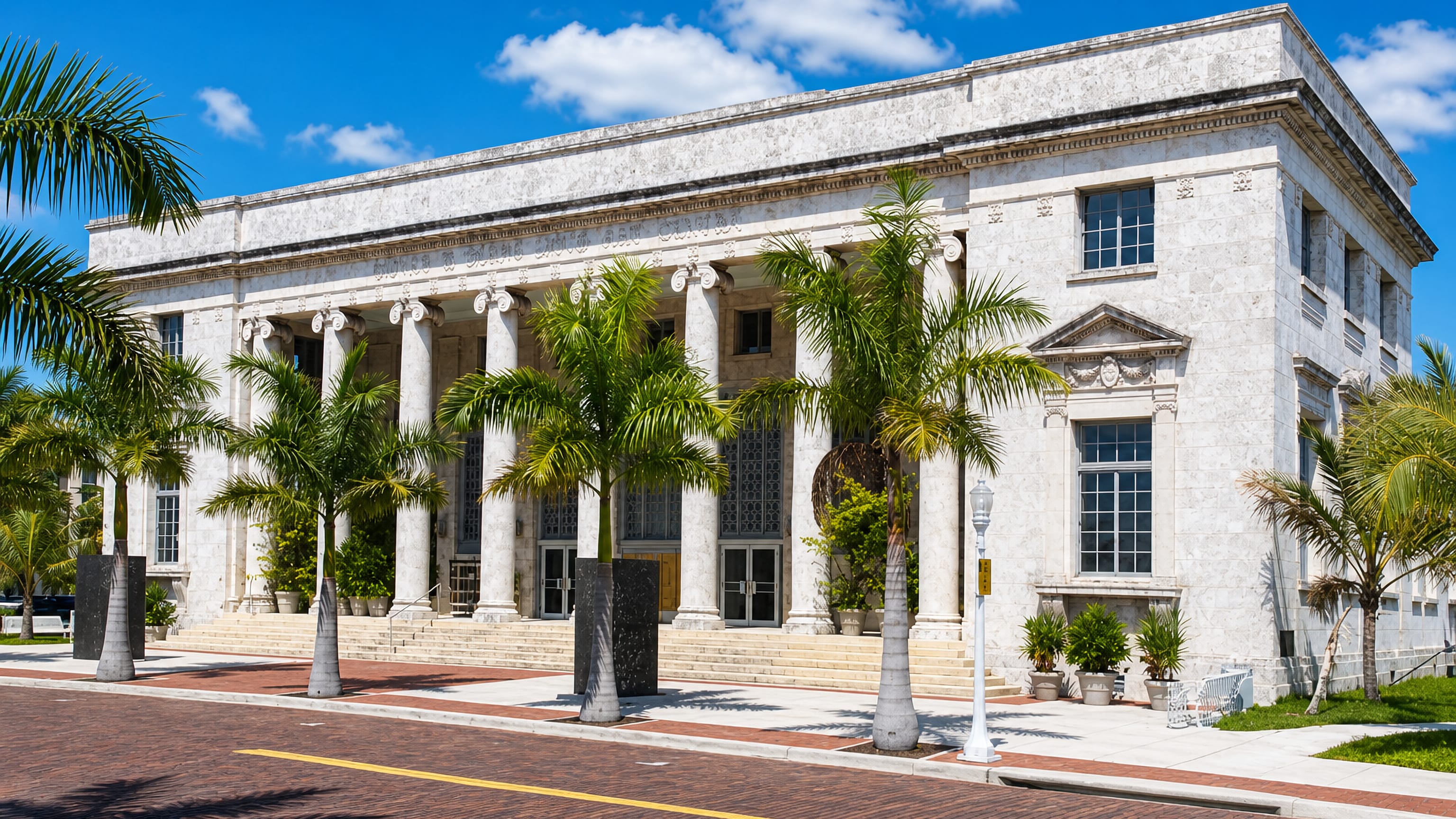 Neoclassical courthouse fronted by royal palms on a red-brick street in downtown Fort Myers, Florida