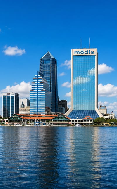 Downtown Jacksonville skyline across the St. Johns River with the Modis tower and blue Main Street Bridge.