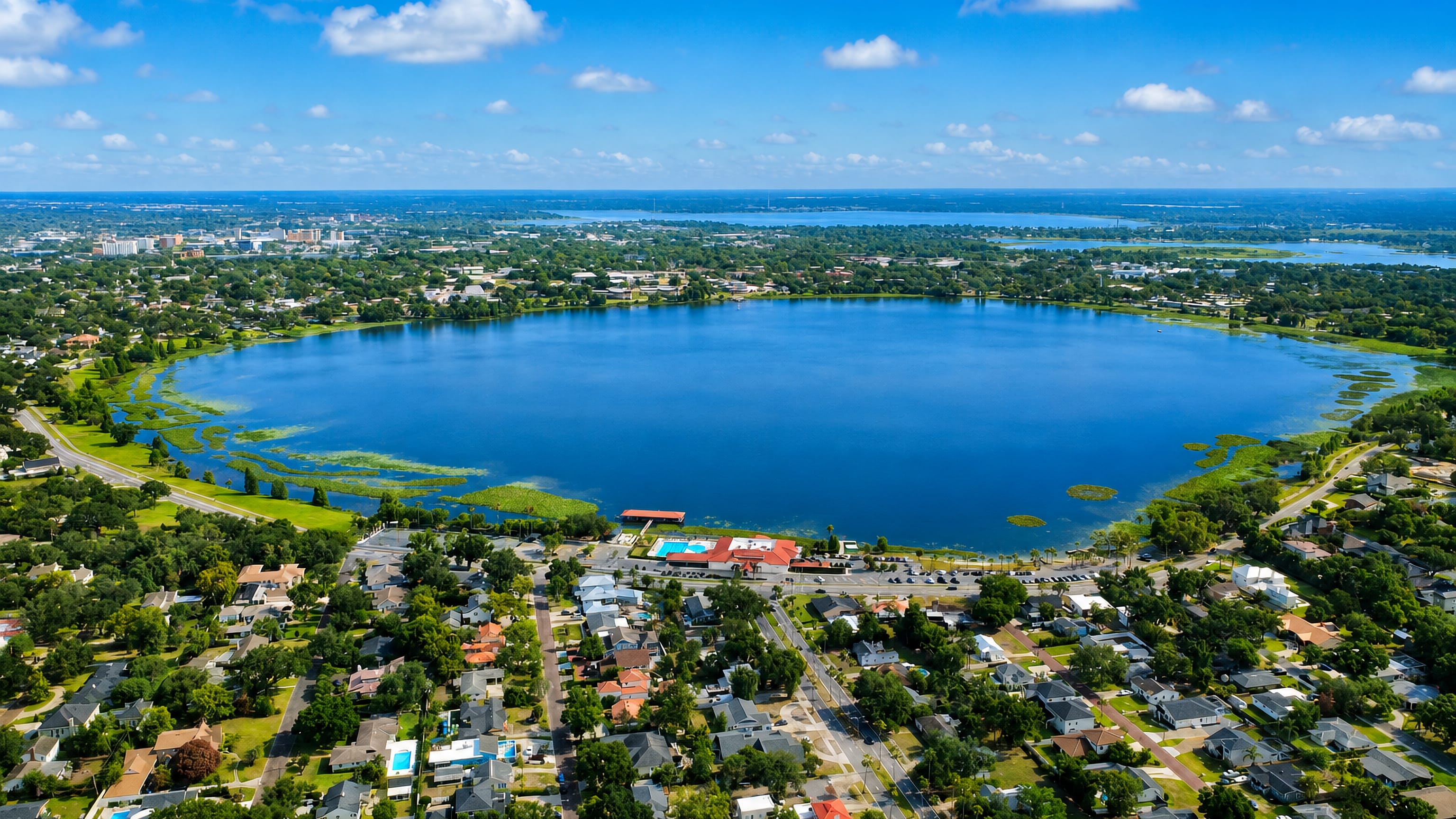 Aerial view of Lakeland, Florida, a broad round lake ringed by lakeside neighbourhoods with downtown in the distance