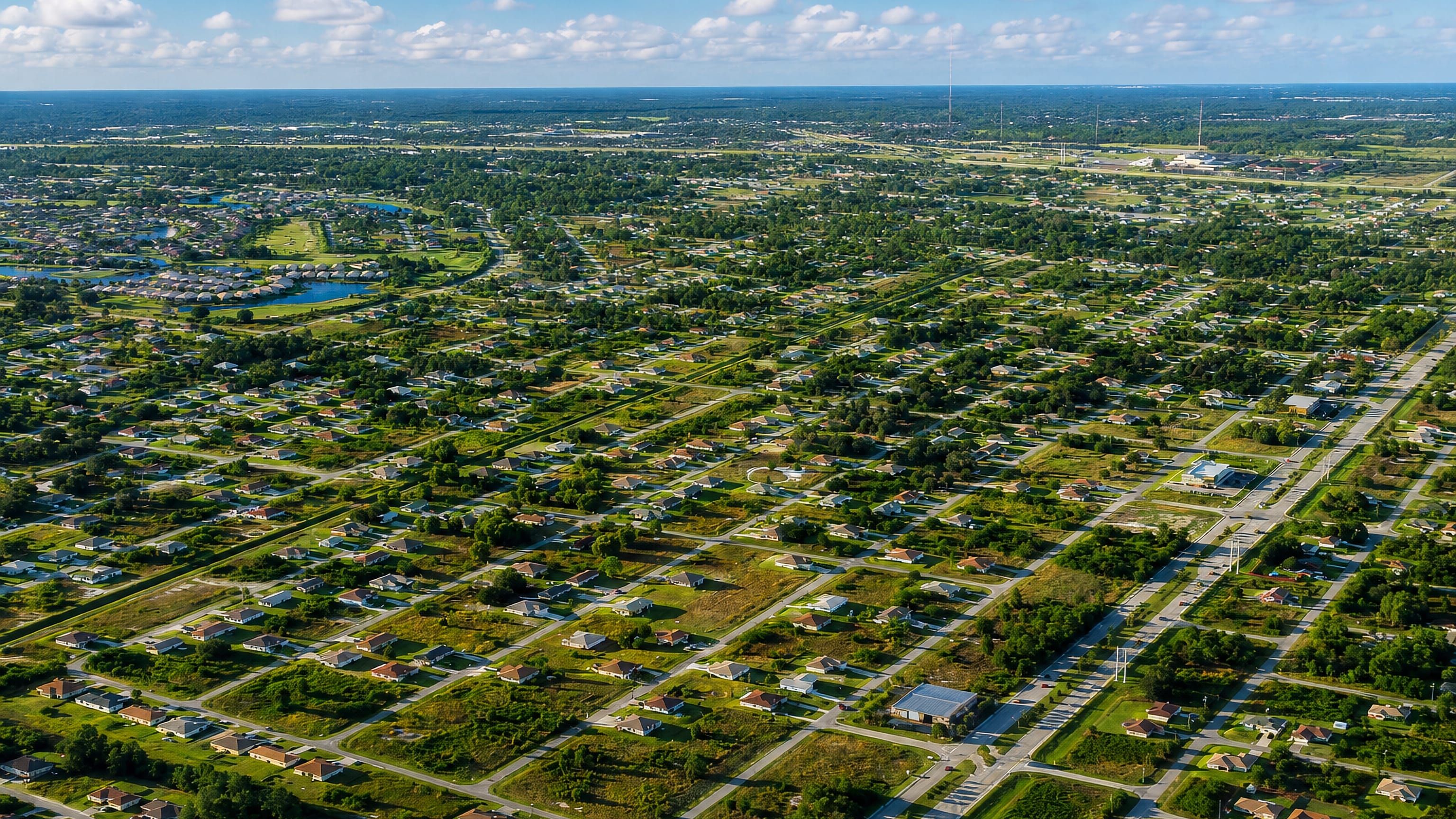 Aerial view of Lehigh Acres, Florida, showing its grid of platted streets, scattered homes and green vacant lots.