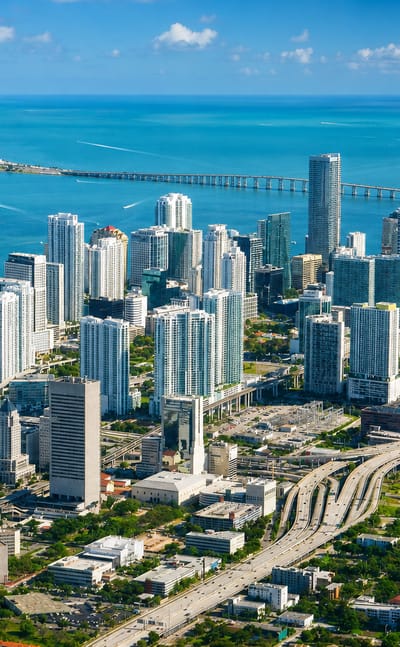 Aerial view of the Miami skyline with Brickell high-rises, Biscayne Bay, a causeway bridge and highway interchange