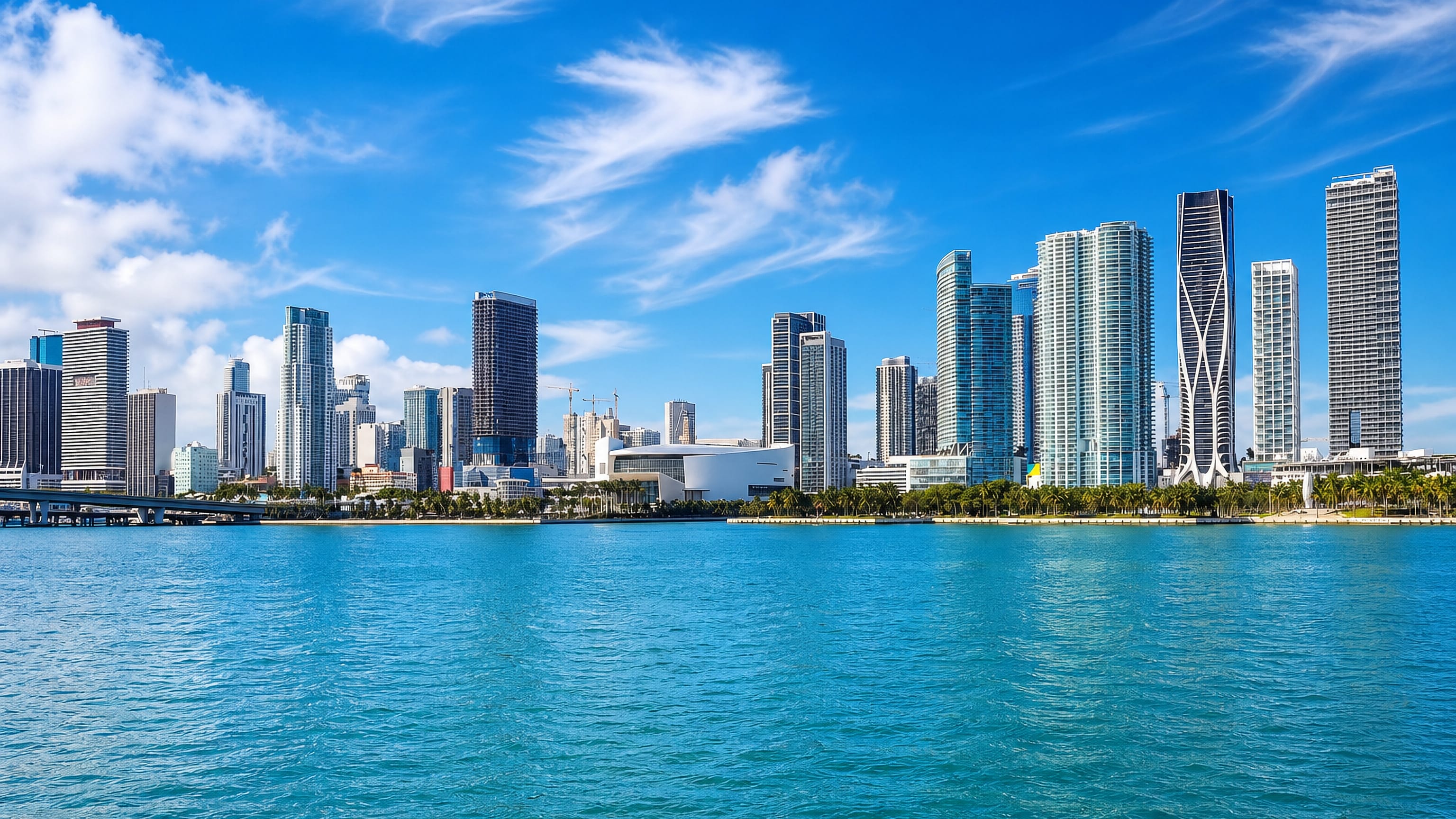 Downtown Miami's high-rise skyline rising above the palms and turquoise water of Biscayne Bay.