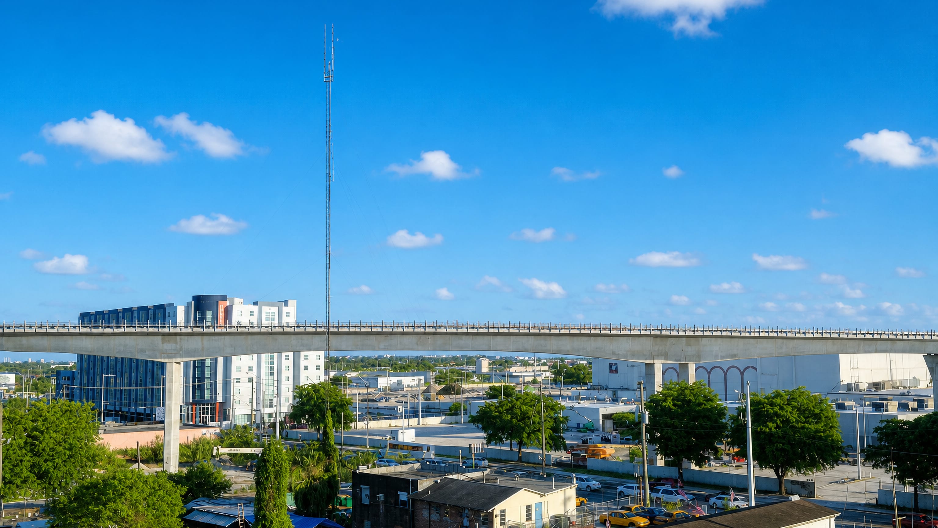 An elevated expressway crosses low-rise blocks and a radio mast in Overtown, Miami.