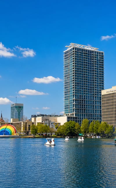 Orlando downtown towers rising over Lake Eola with its fountain and swan pedal boats.