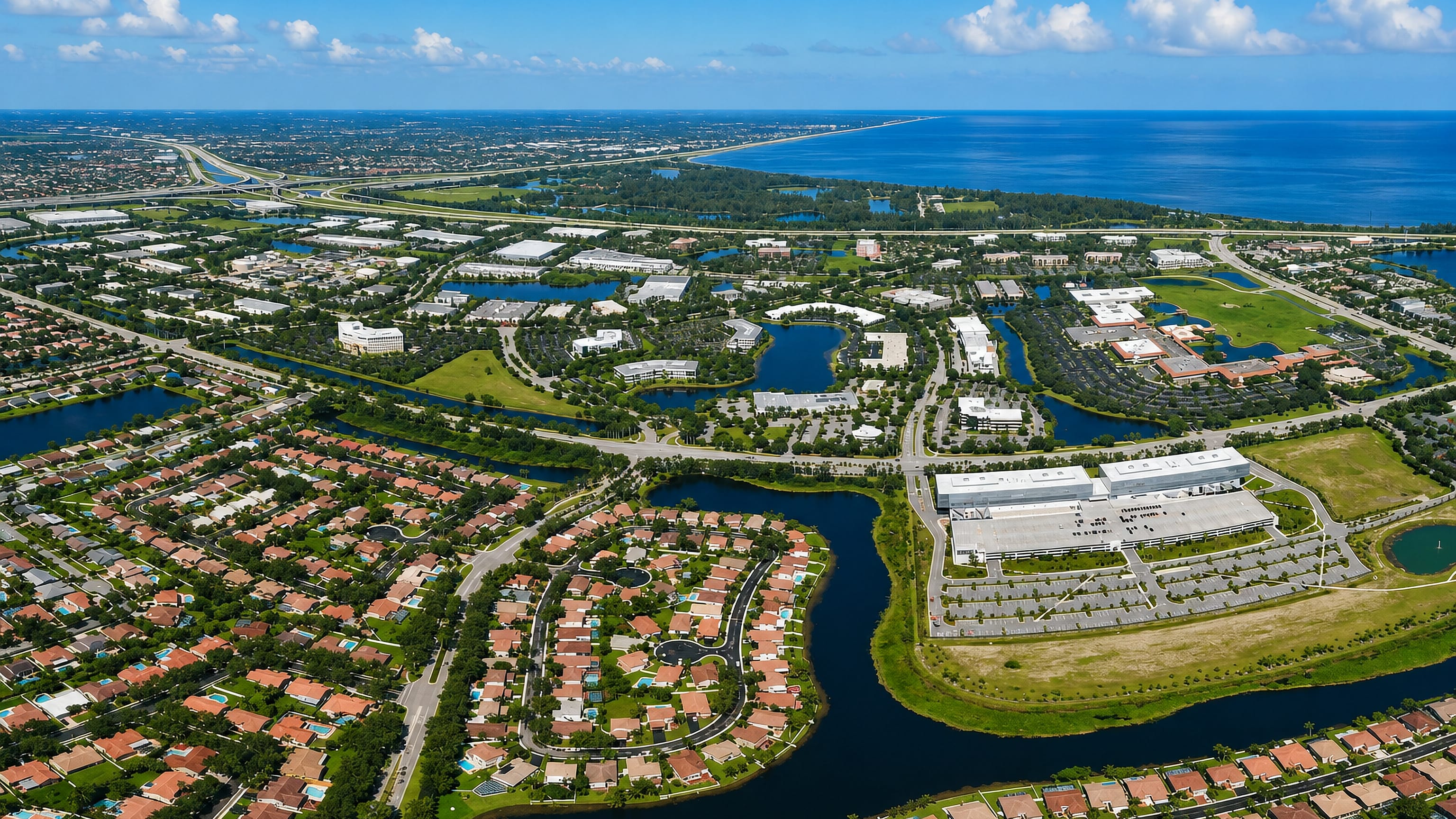 Aerial view of Sunrise, Florida: tile-roofed subdivisions, canals and office parks with the Atlantic beyond.