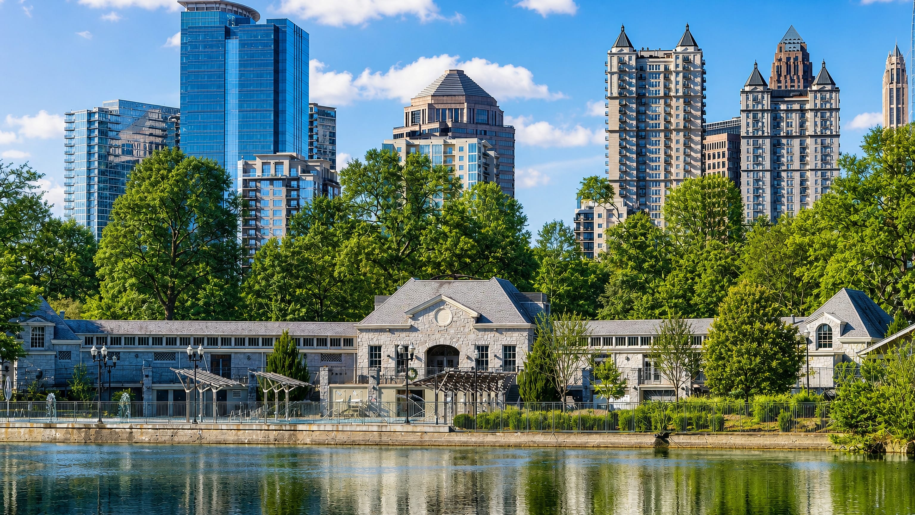 Midtown Atlanta's towers rise beyond Piedmont Park's lake and the stone community centre on its shore.
