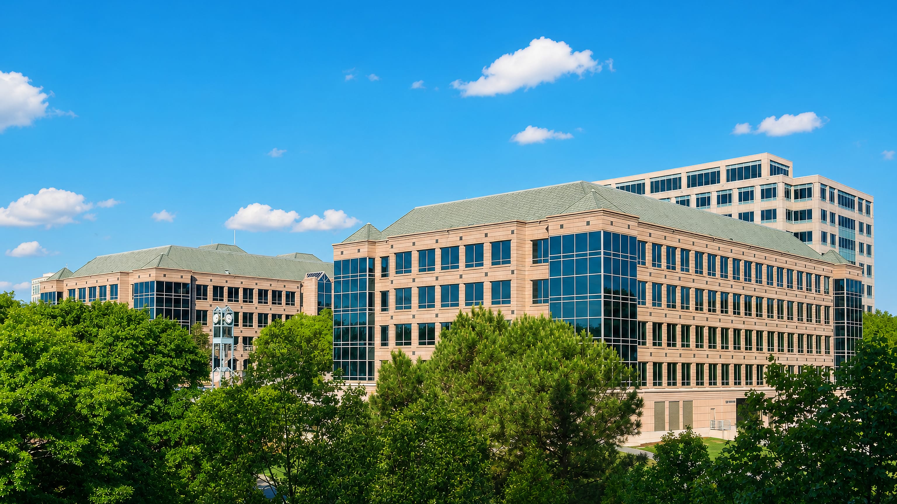 Mid-rise office buildings rising above summer treetops in Brookhaven, Georgia, under a clear blue sky.