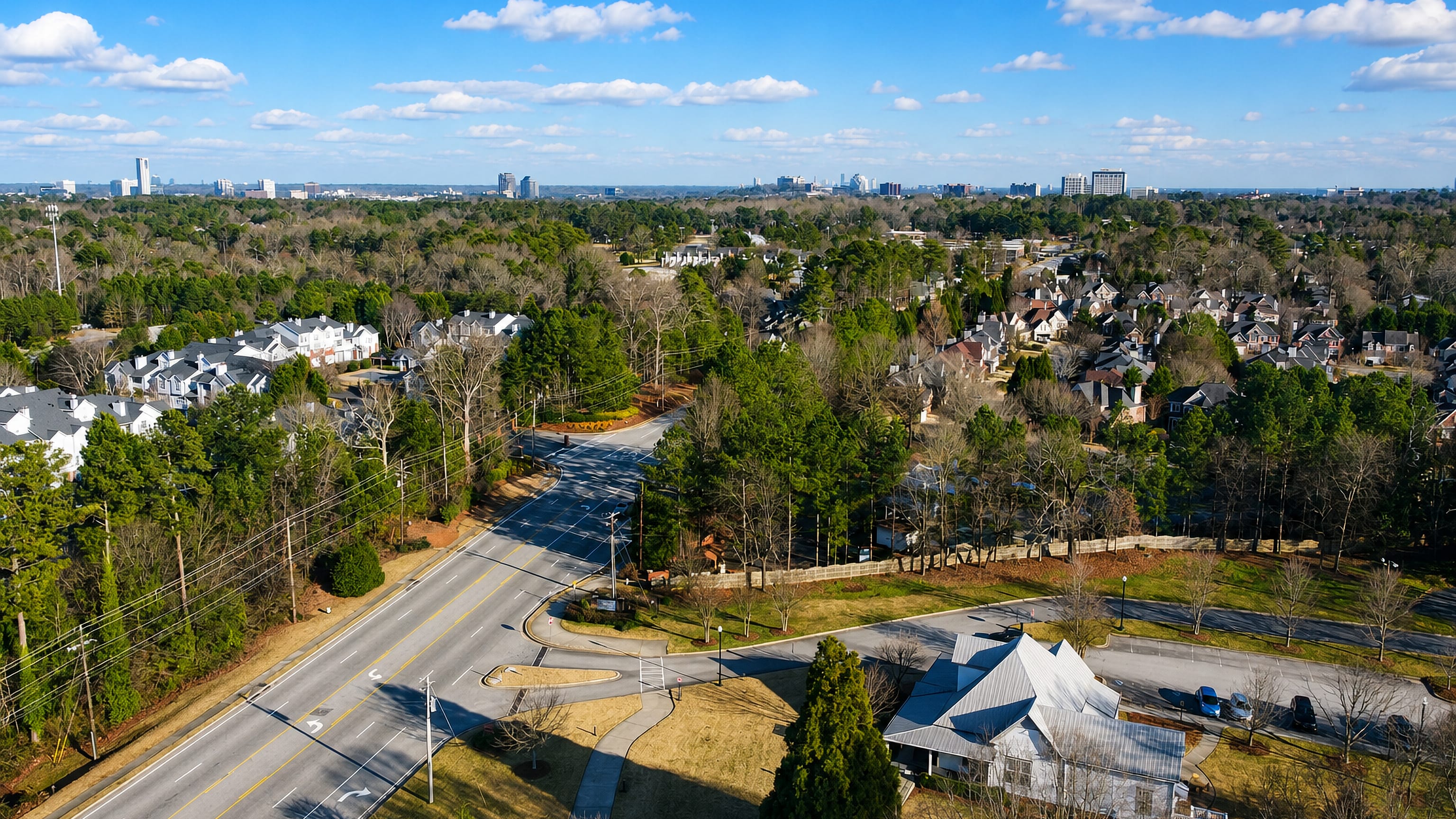 Smyrna, Georgia from the air: wooded suburban streets and townhomes with the Atlanta skyline low on the horizon.