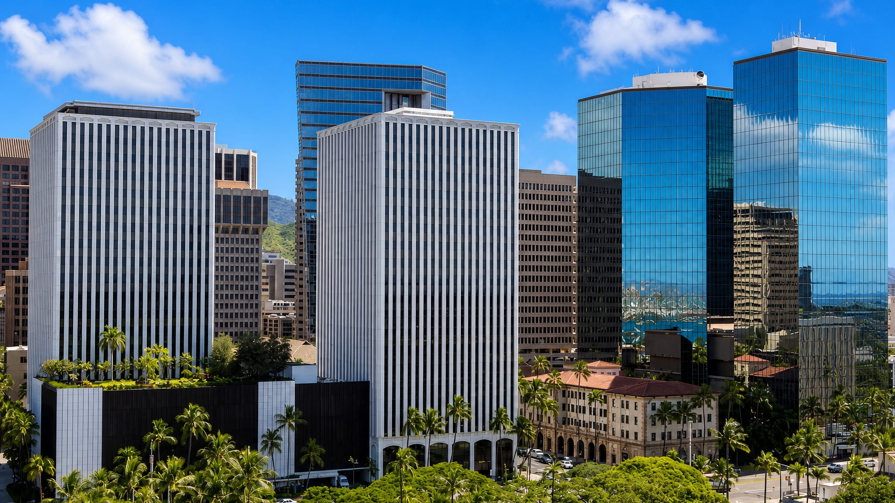 Downtown Honolulu's office towers framed by palms, with the green Koolau ridge rising behind.