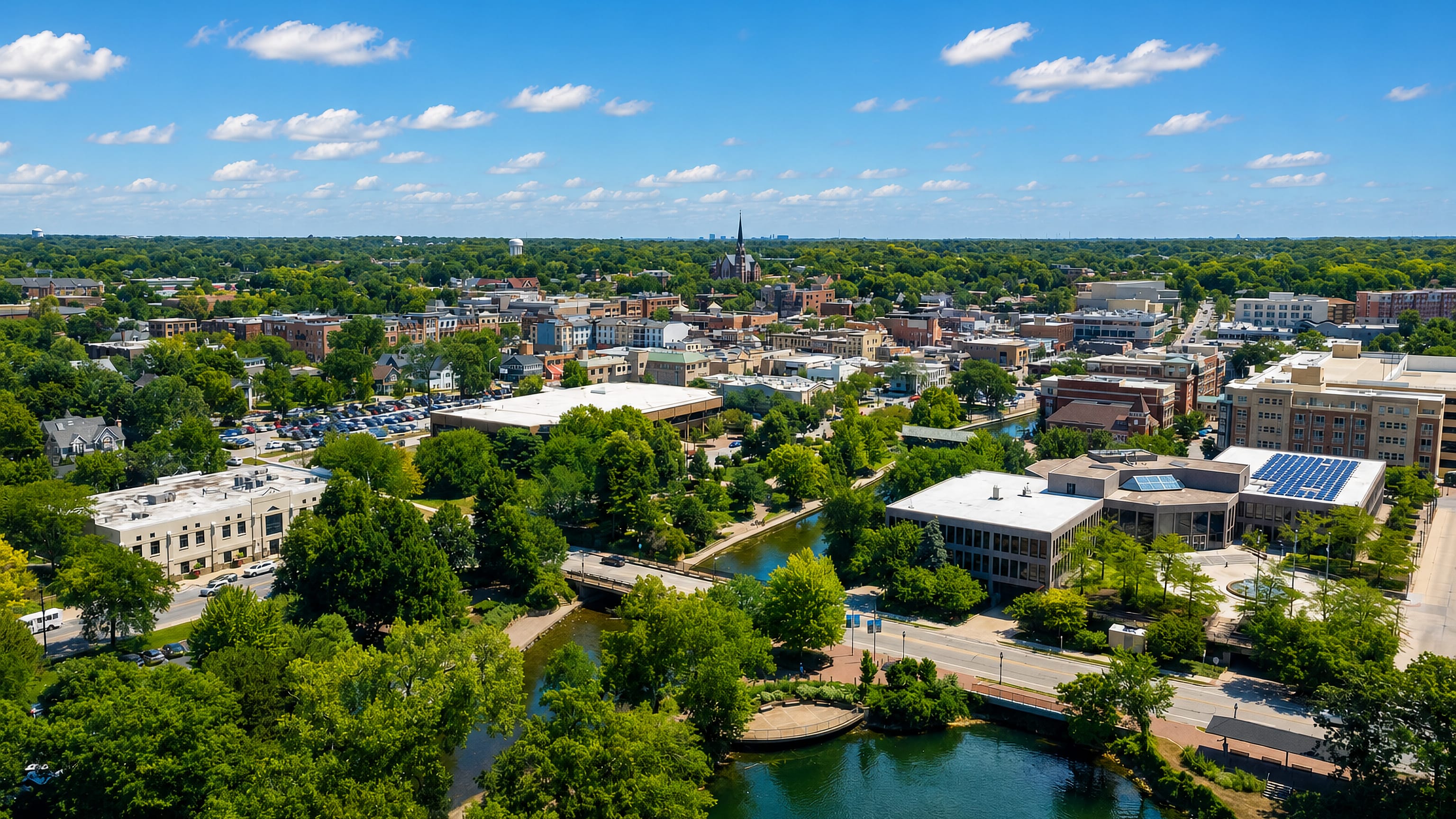 Downtown Naperville, Illinois, from above, with the DuPage Riverwalk winding past a tall church spire.