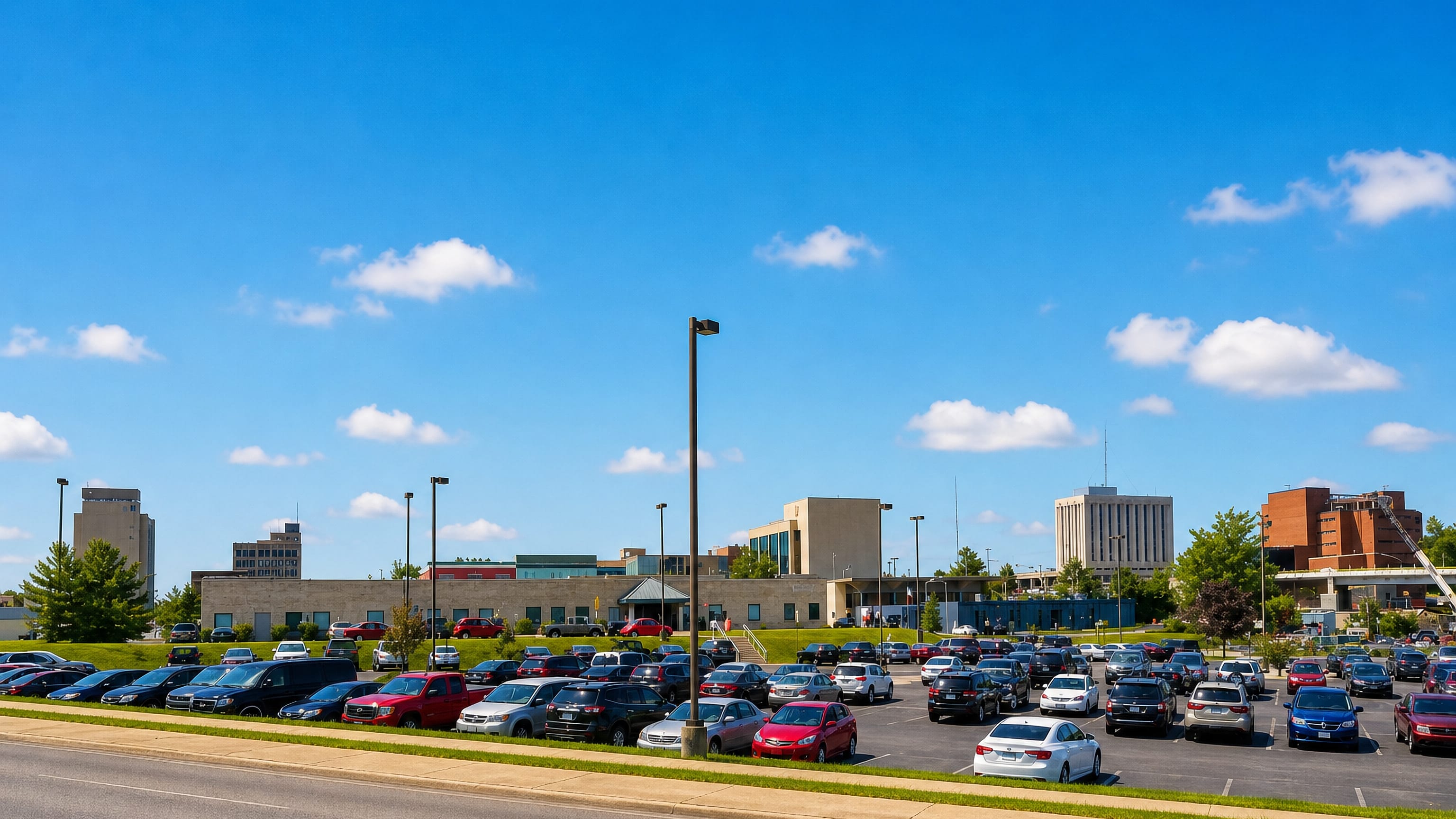 Downtown Anderson, Indiana's low skyline of offices and brick blocks beyond a filled parking lot.
