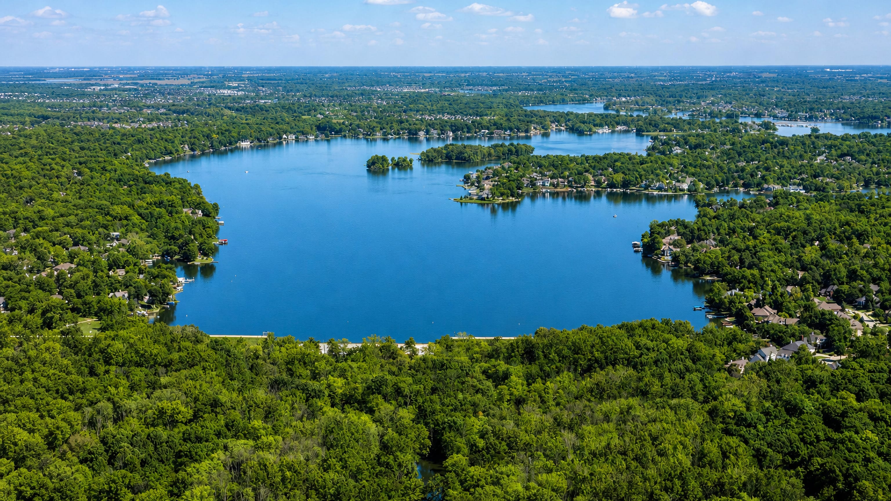 Wooded reservoir ringed by lakeside homes and dense forest in Fishers, Indiana, seen from the air