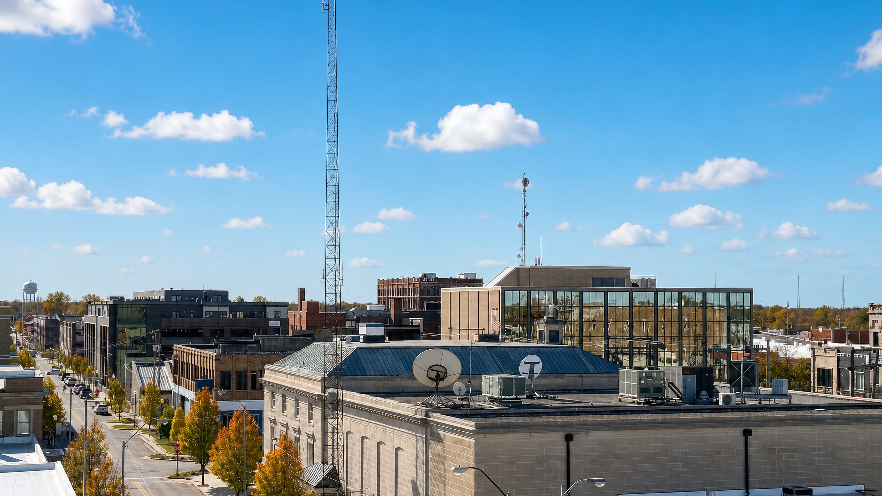 Downtown Kokomo, Indiana, with its water tower, autumn trees and low brick blocks seen from a rooftop.