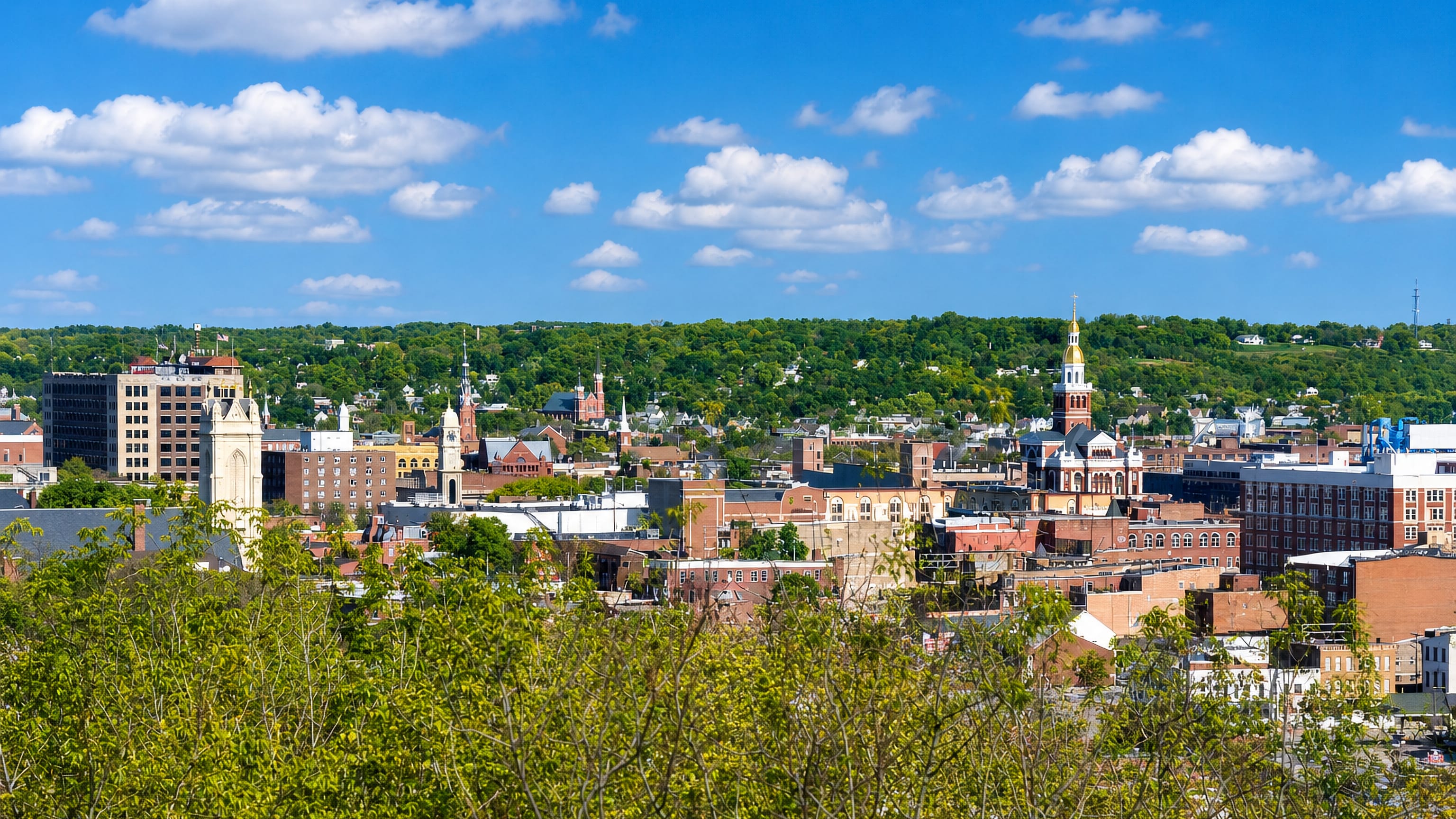 Dubuque, Iowa, downtown with the gold-domed county courthouse and church spires below wooded bluffs.
