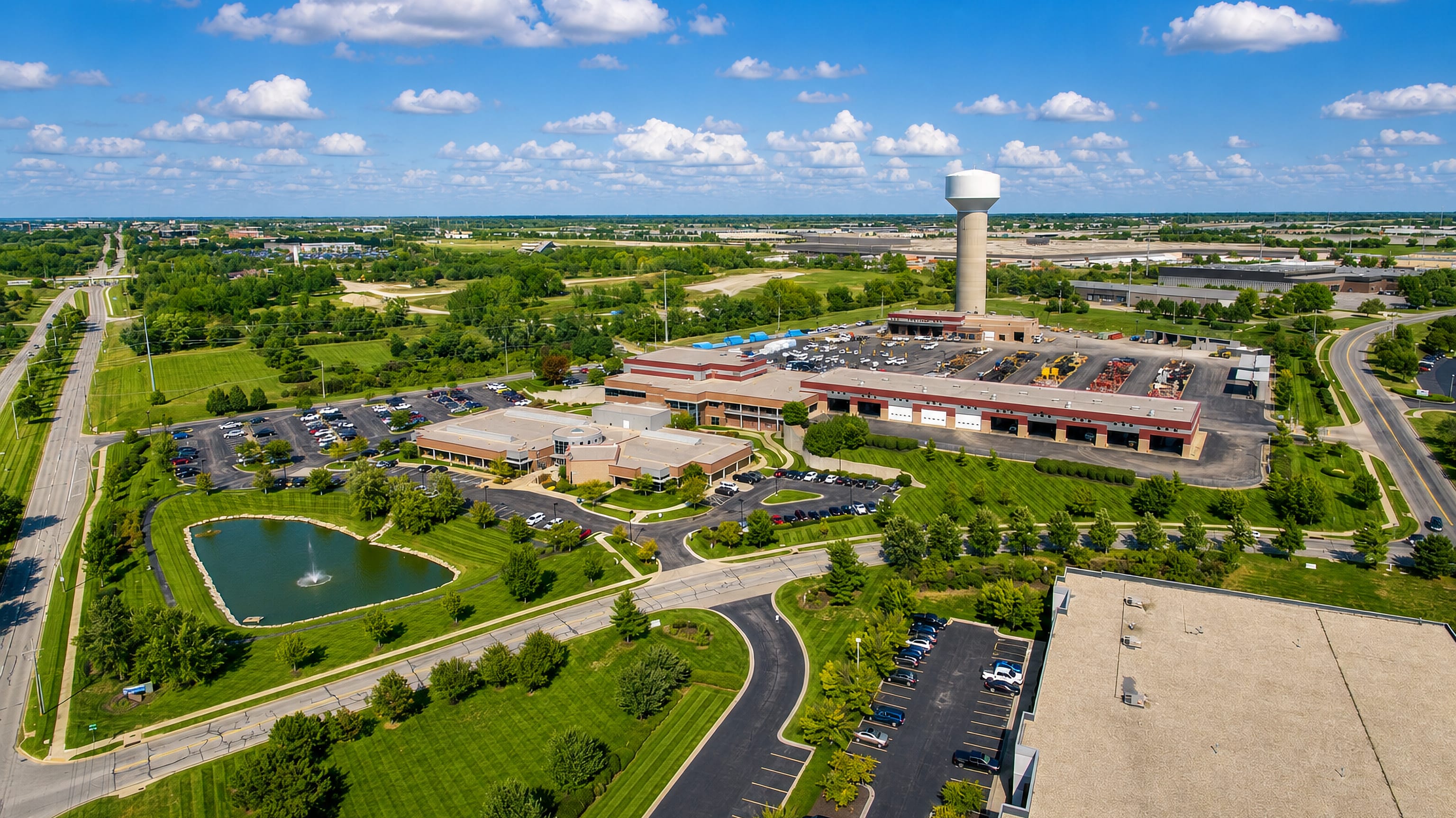 Aerial view of Lenexa, Kansas, showing a water tower, municipal buildings, parking lots and landscaped green space.