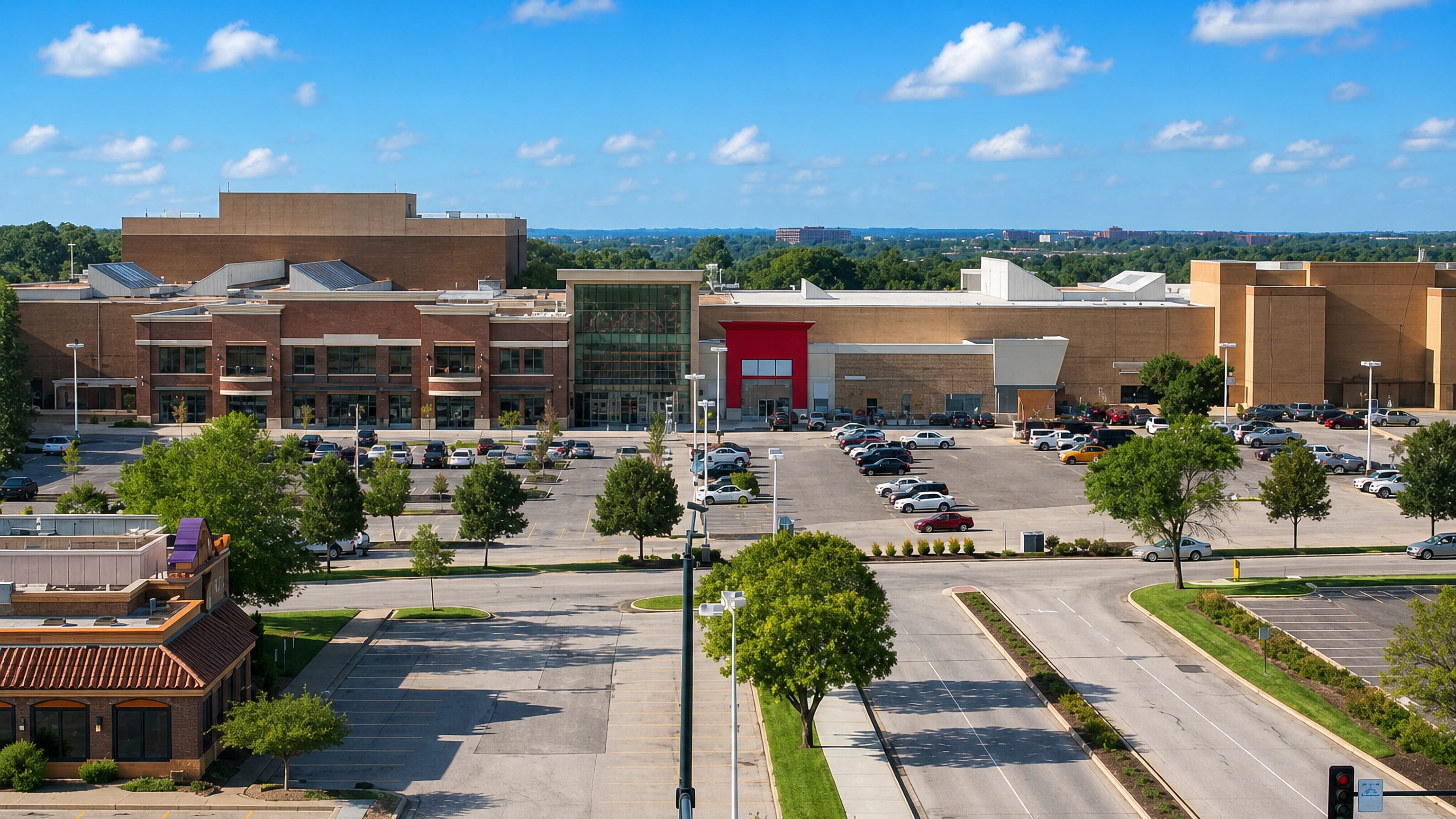 Suburban shopping mall, parking lots and a tree-lined arterial road under clear skies in Overland Park, Kansas