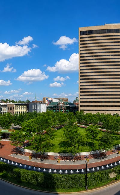 Wide view of downtown Lexington, Kentucky's high-rise towers above a landscaped park and curving streets.