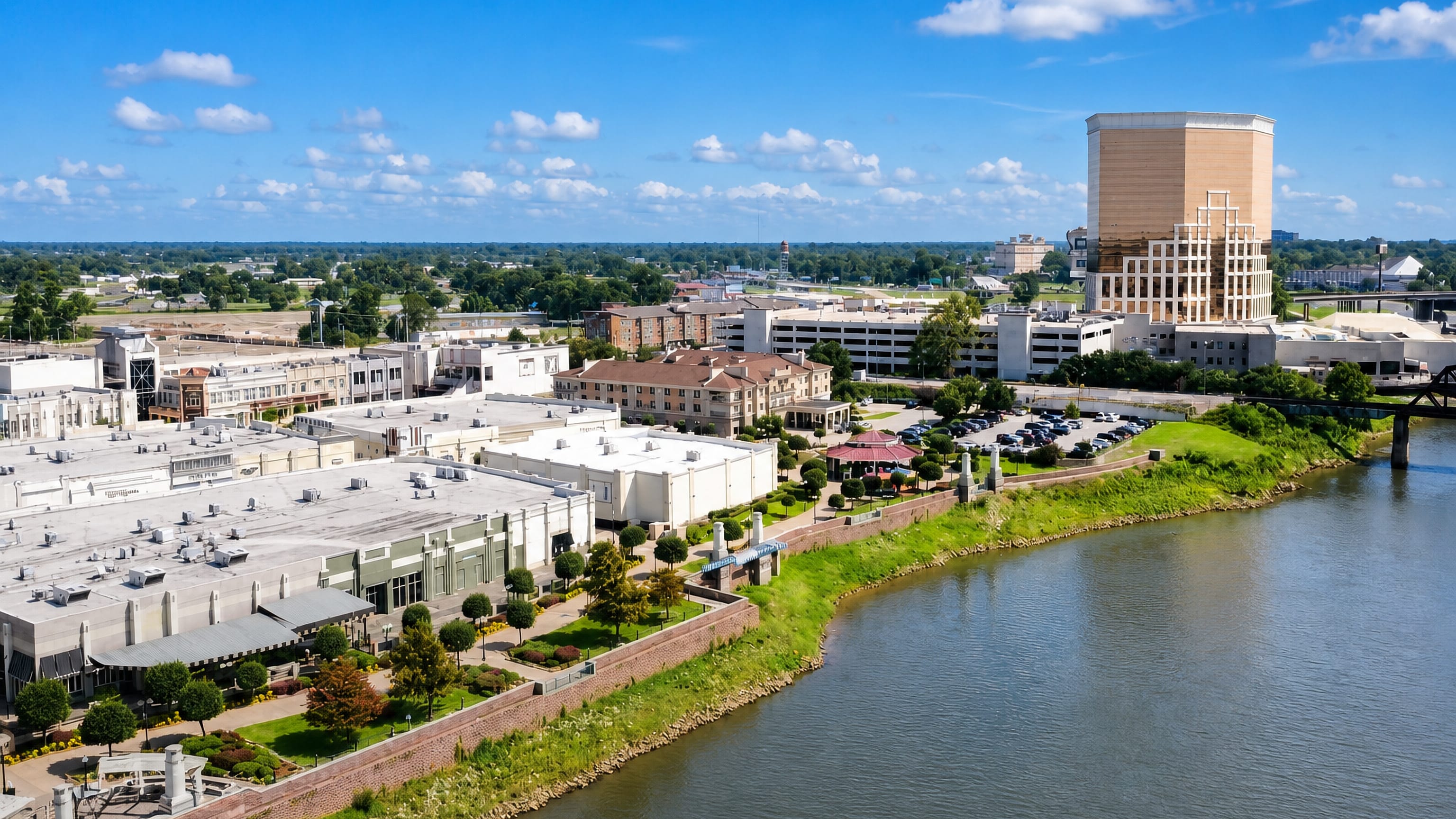 Bossier City's Red River waterfront with riverside boardwalk shops, a landscaped promenade and a hotel tower.