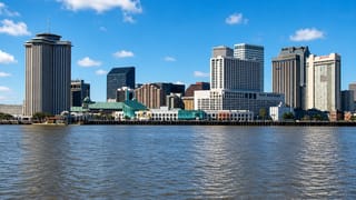 New Orleans central business district skyline seen across the Mississippi River with riverfront hotels.