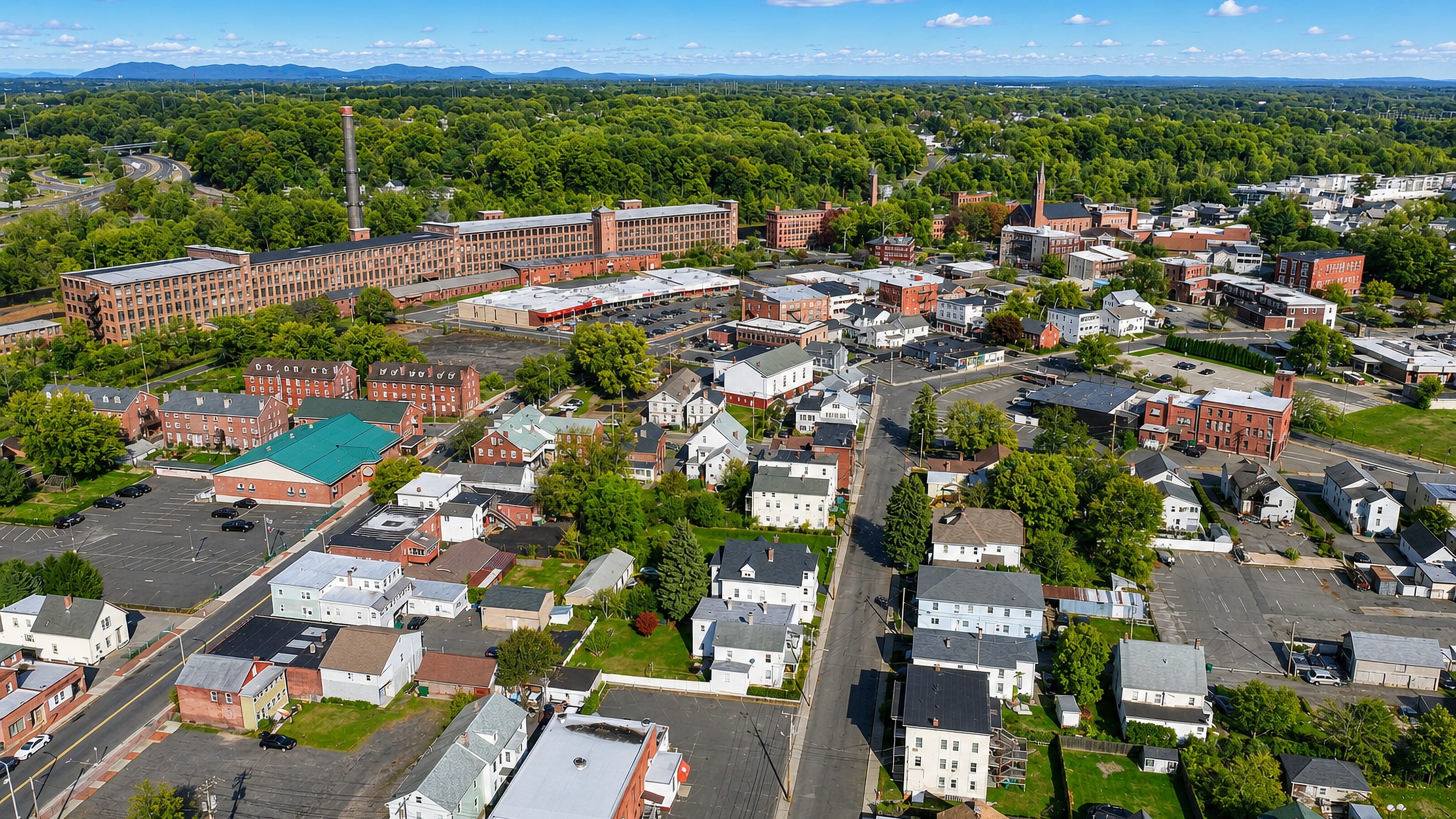 Aerial view of Chicopee, Massachusetts, with its long brick mill, smokestack and triple-decker streets