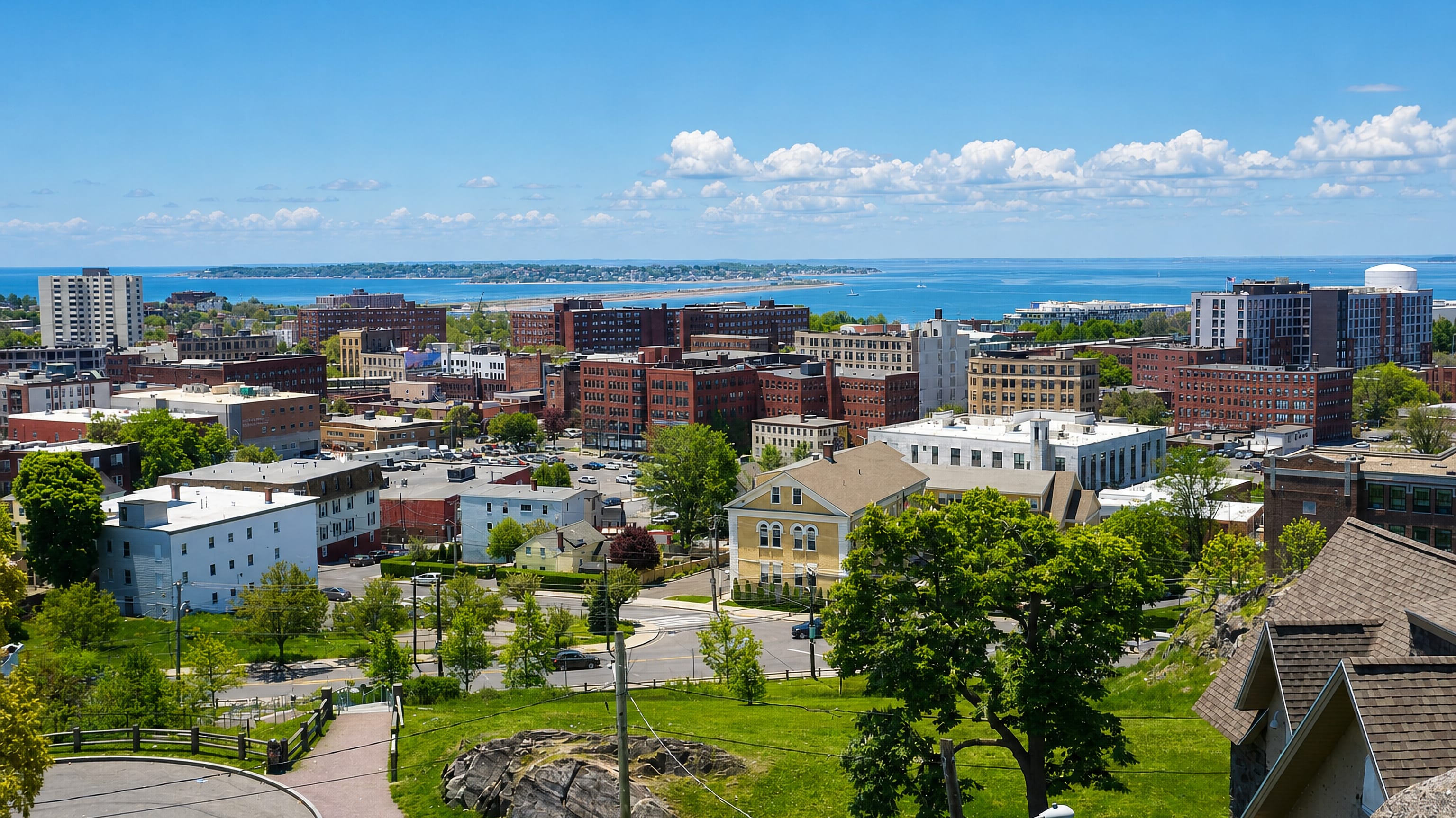 Brick downtown Lynn, Massachusetts, seen from a hilltop with the Atlantic shoreline stretching beyond.