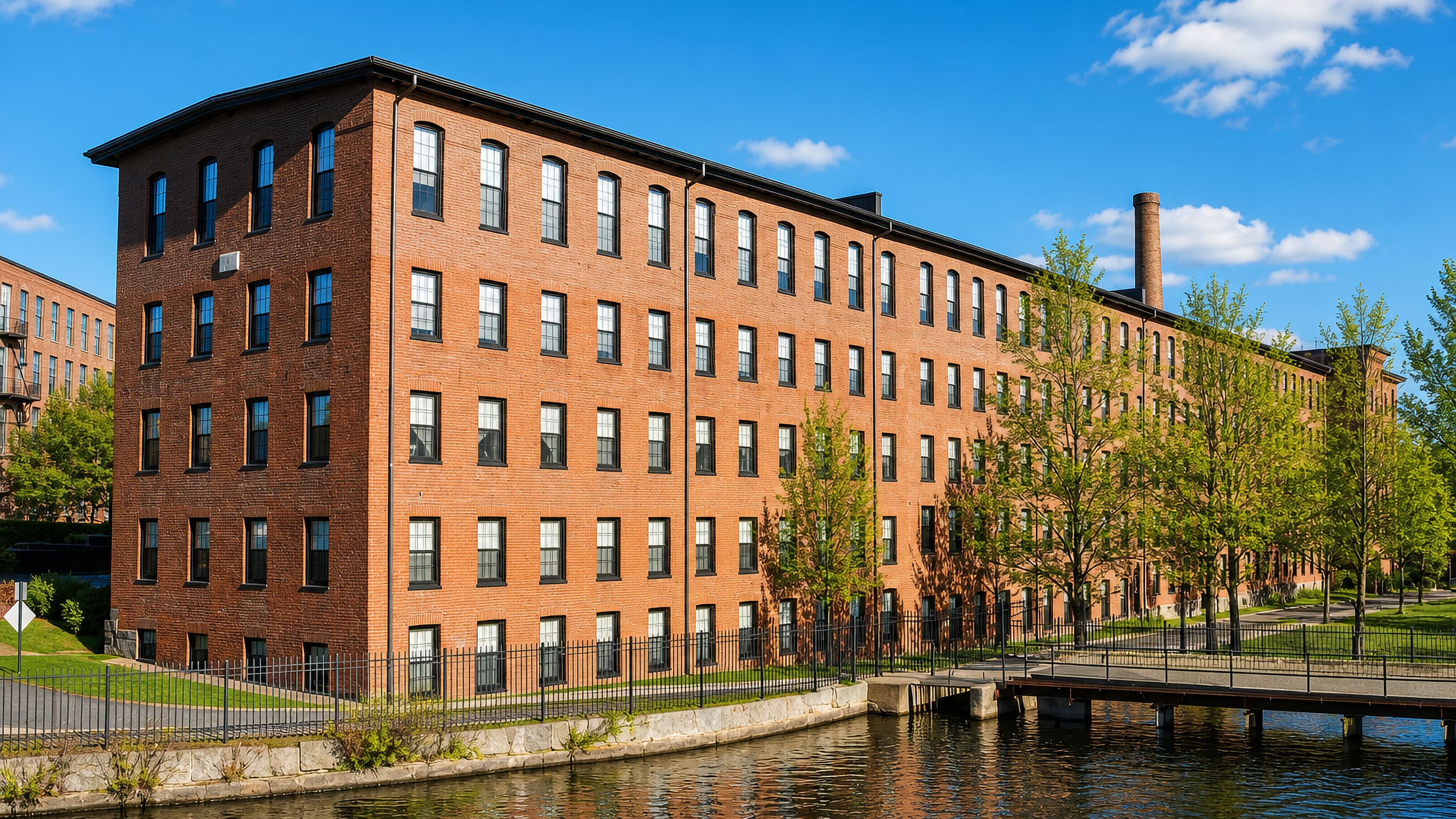 Red-brick 19th-century mill buildings lining the canal on the Charles River in Waltham, Massachusetts.