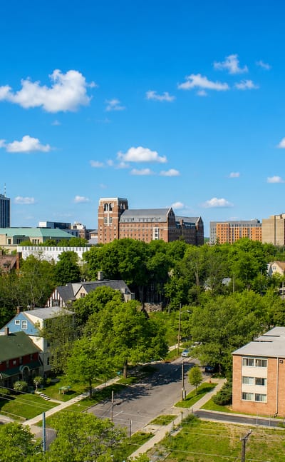 Aerial view of Ann Arbor, Michigan with a university clock tower rising above leafy tree-lined neighborhoods.