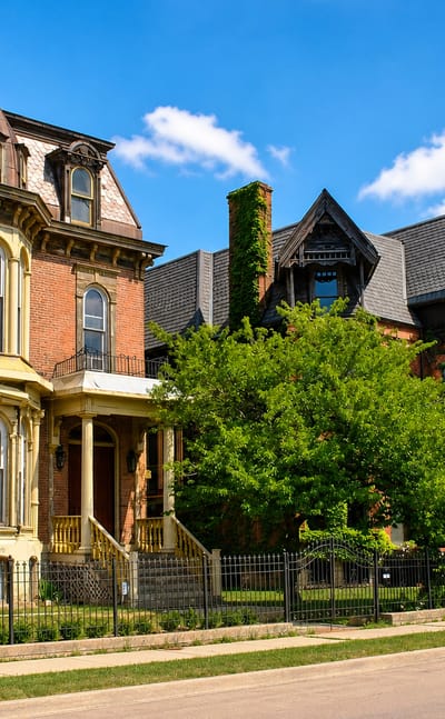 Restored Victorian Gothic mansions with ornate bay windows lining a street in Brush Park Historic District, Detroit.