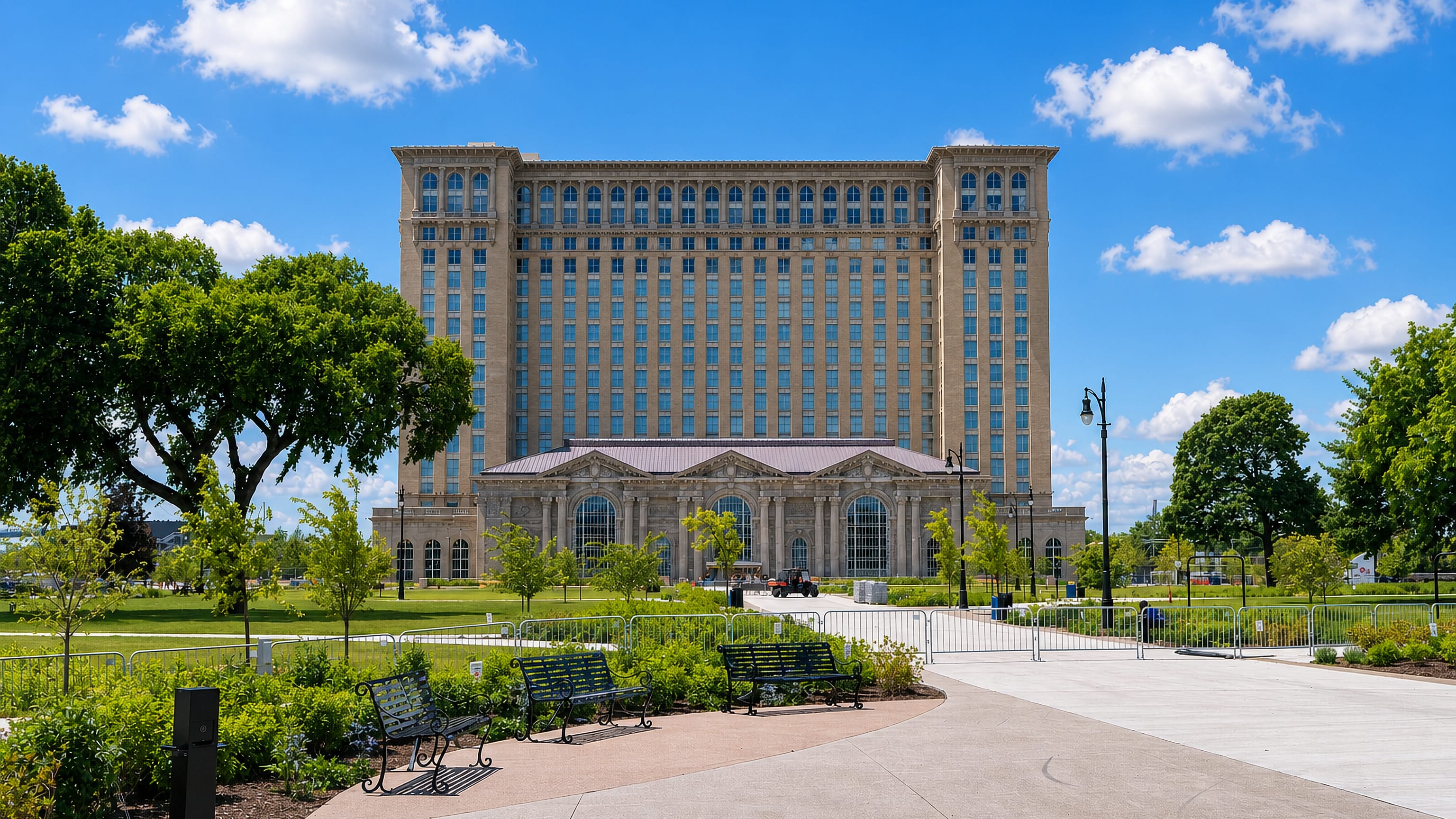 Michigan Central Station towering over a landscaped park in Corktown, Detroit, under a blue summer sky