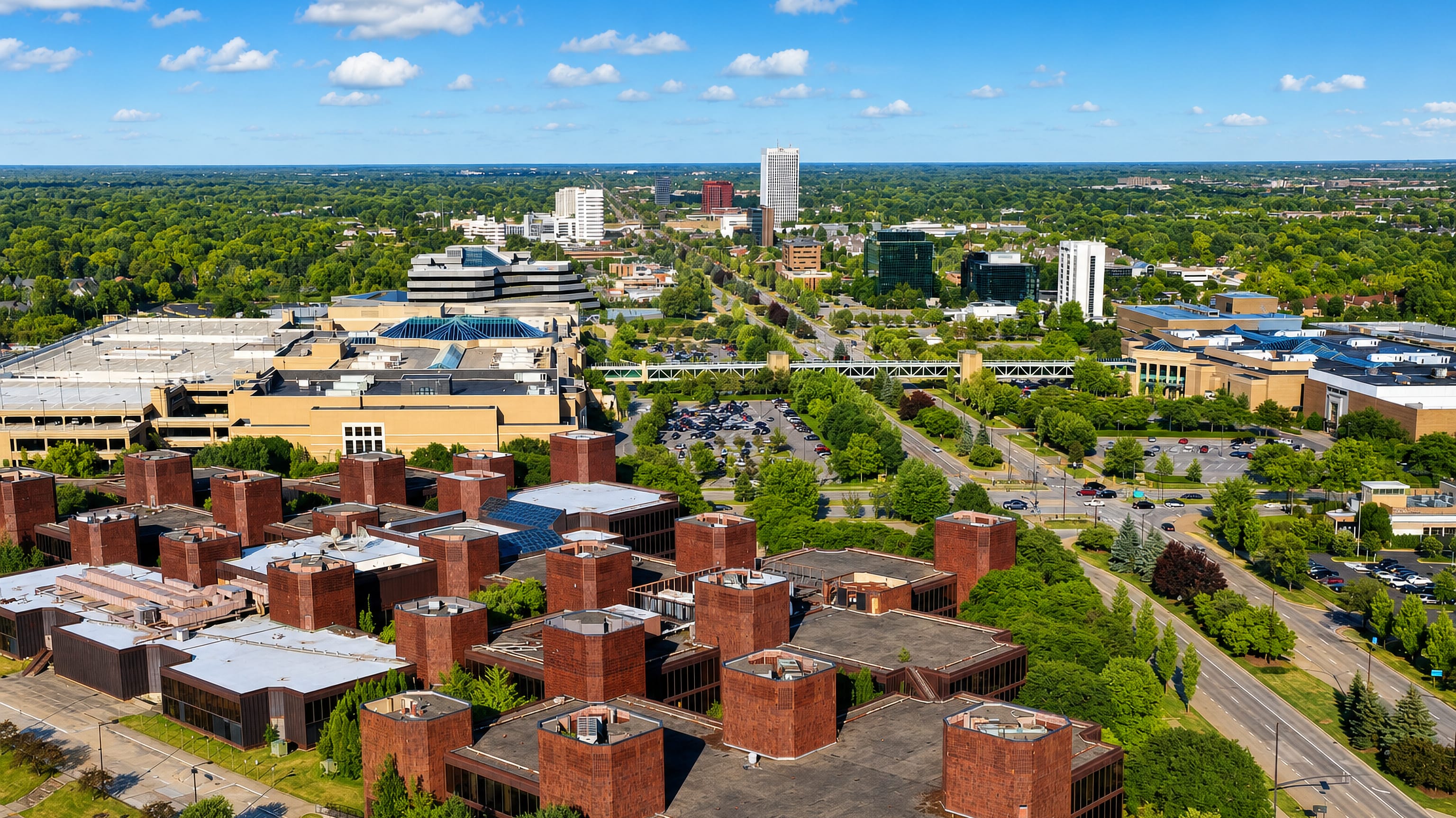 Brick office campuses, a mall skywalk and distant towers rising over the leafy suburbs of Troy, Michigan.