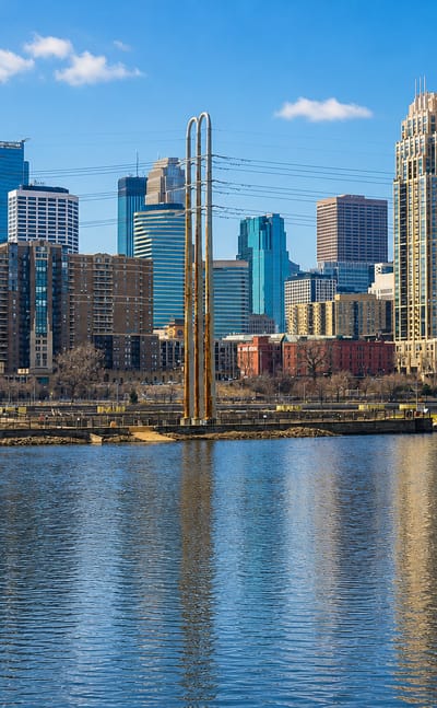 Minneapolis's downtown skyline across the Mississippi River beside the arched Third Avenue Bridge.