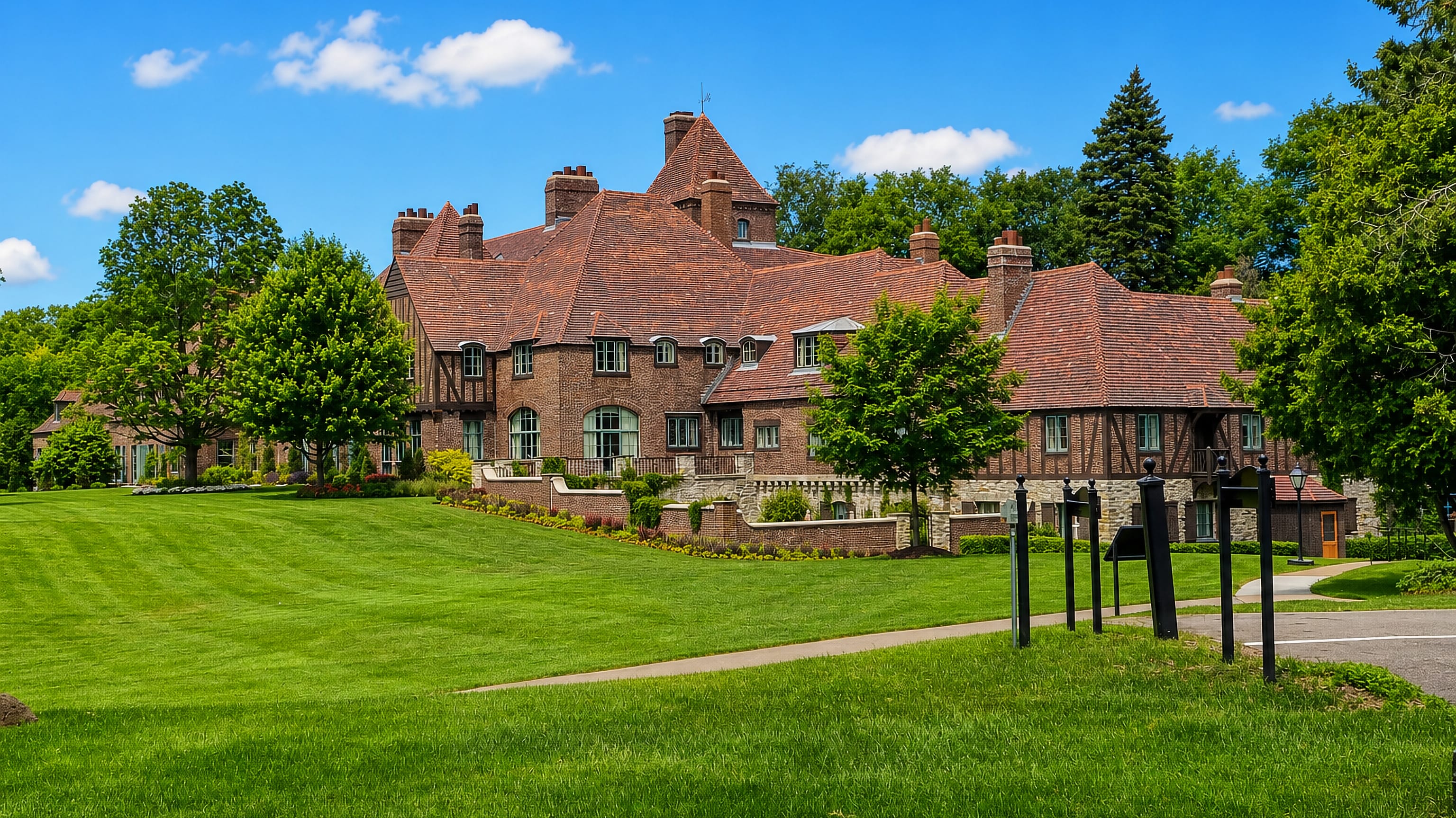 A brick Tudor-style estate house and mown lawns among mature trees in Minnetonka, Minnesota