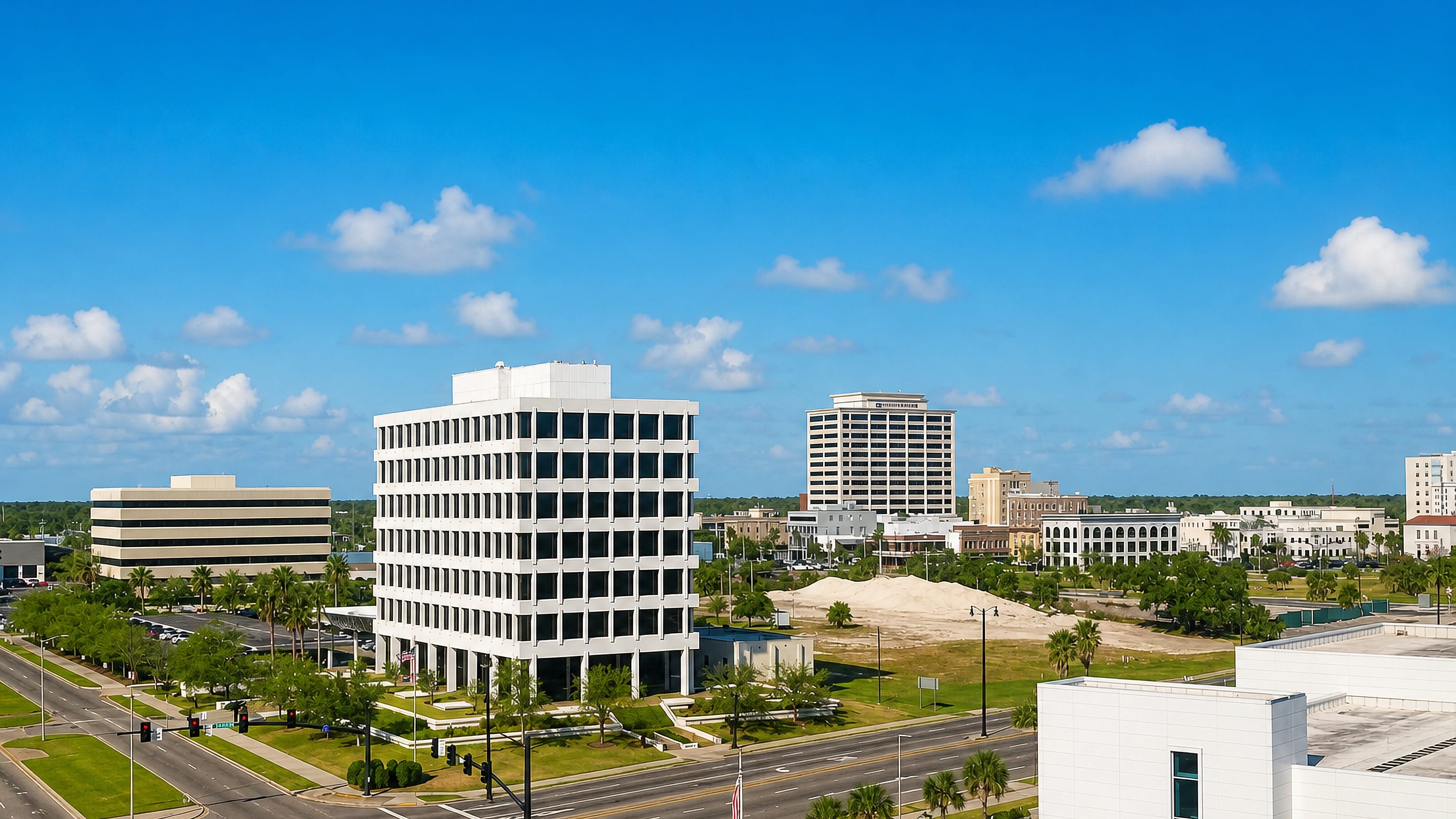 Downtown Gulfport, Mississippi, from above: a white mid-rise office tower, palm-lined boulevards and low brick blocks.