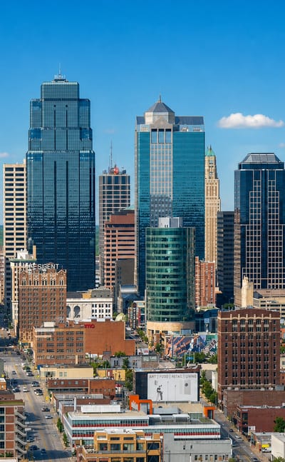 Downtown Kansas City skyline with the crown-topped One Kansas City Place and Art Deco towers under blue sky.