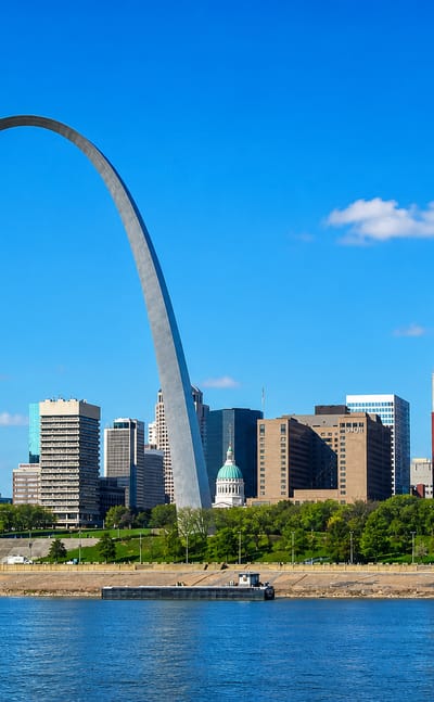 St. Louis Gateway Arch framing the downtown skyline and courthouse dome above the Mississippi riverfront.
