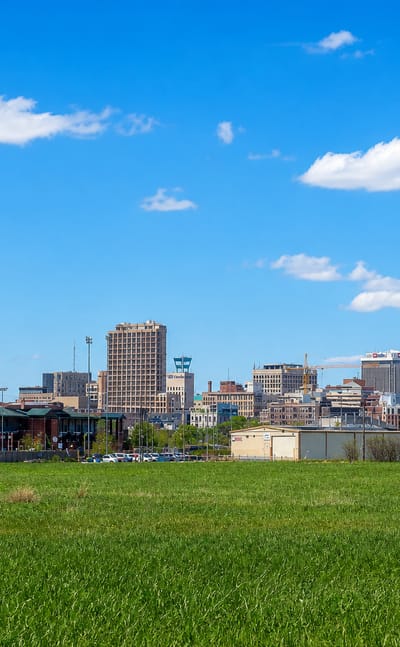 Lincoln, Nebraska skyline across a green field, with the Nebraska State Capitol tower at center.
