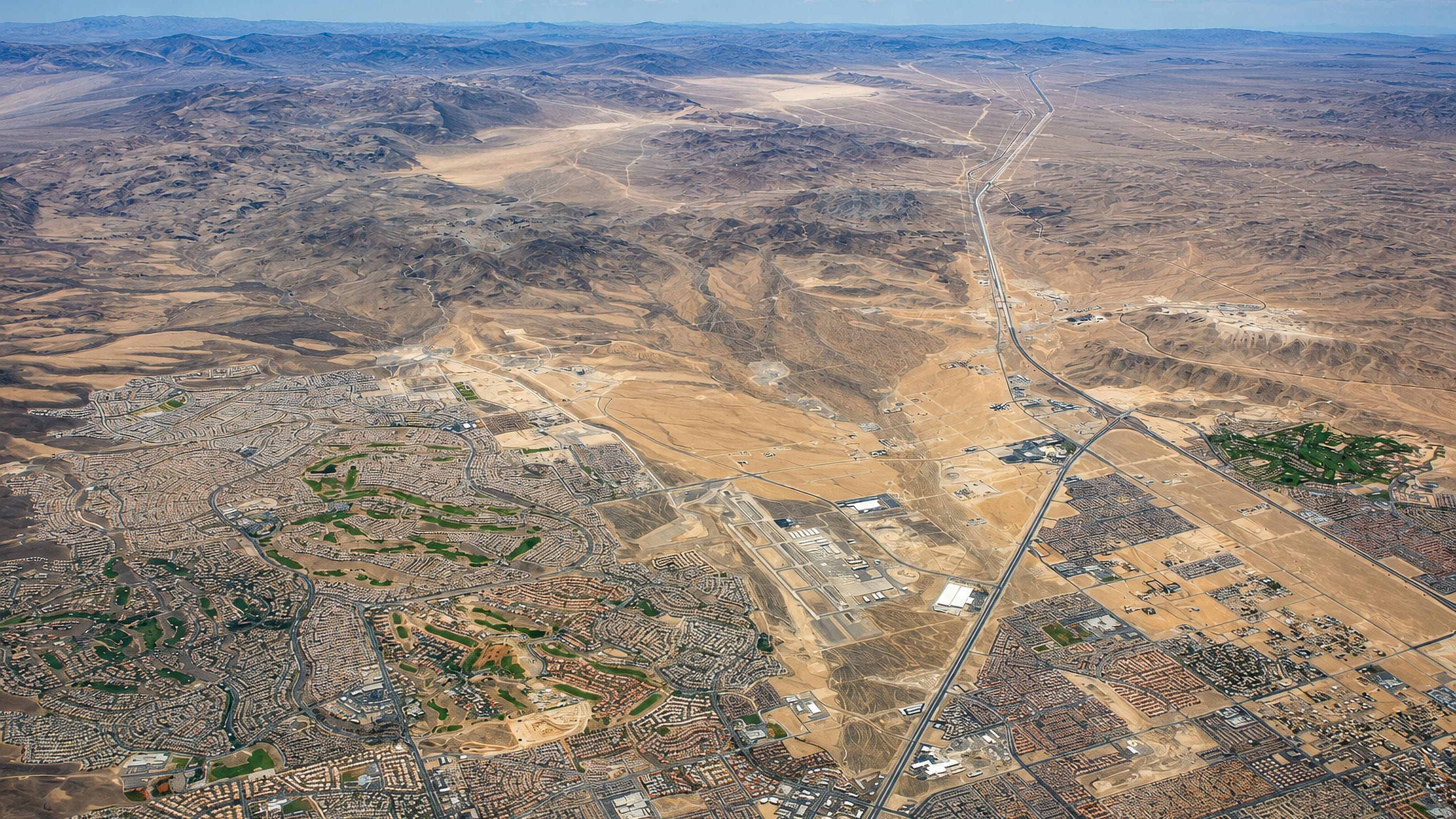 High aerial of Enterprise, Nevada, its desert subdivisions and golf courses stretching toward bare ranges.