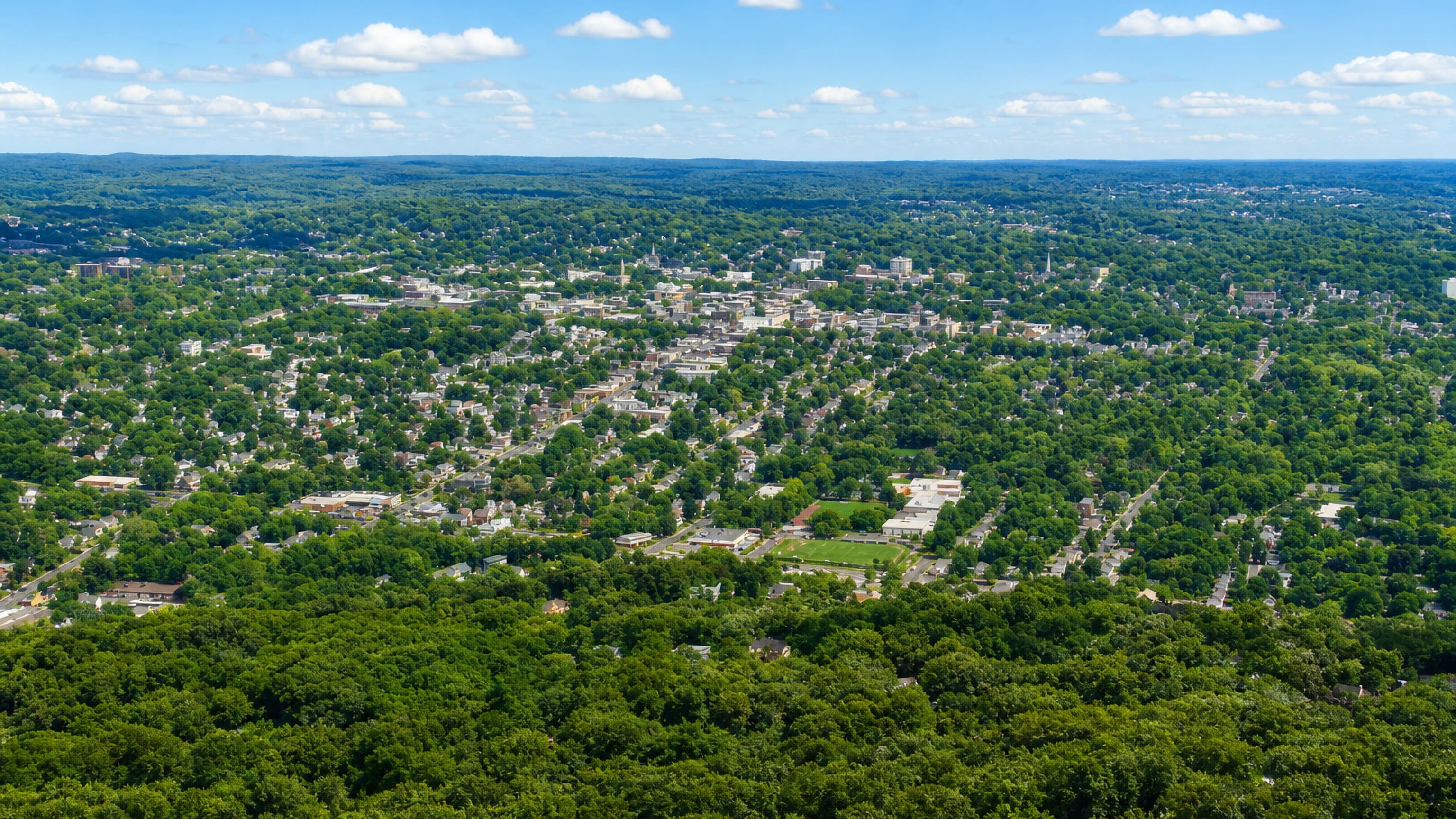 Aerial view over Plainfield, New Jersey, a low downtown set among dense summer tree cover and rolling hills