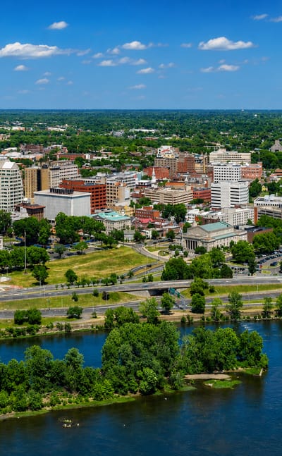 Aerial of Trenton, New Jersey along the Delaware River, with the gold-domed State House at left.