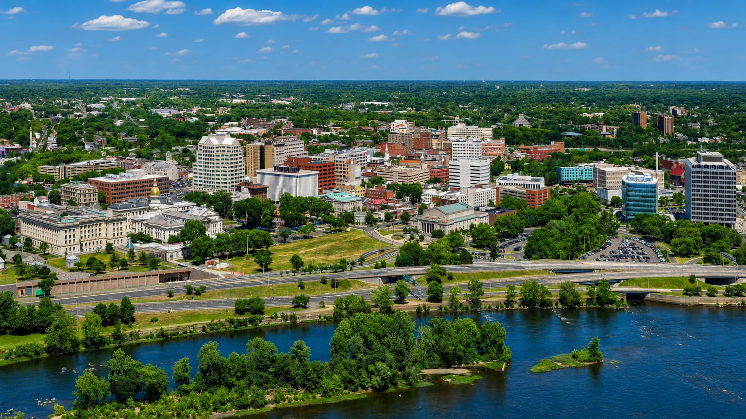 Aerial of Trenton, New Jersey along the Delaware River, with the gold-domed State House at left.