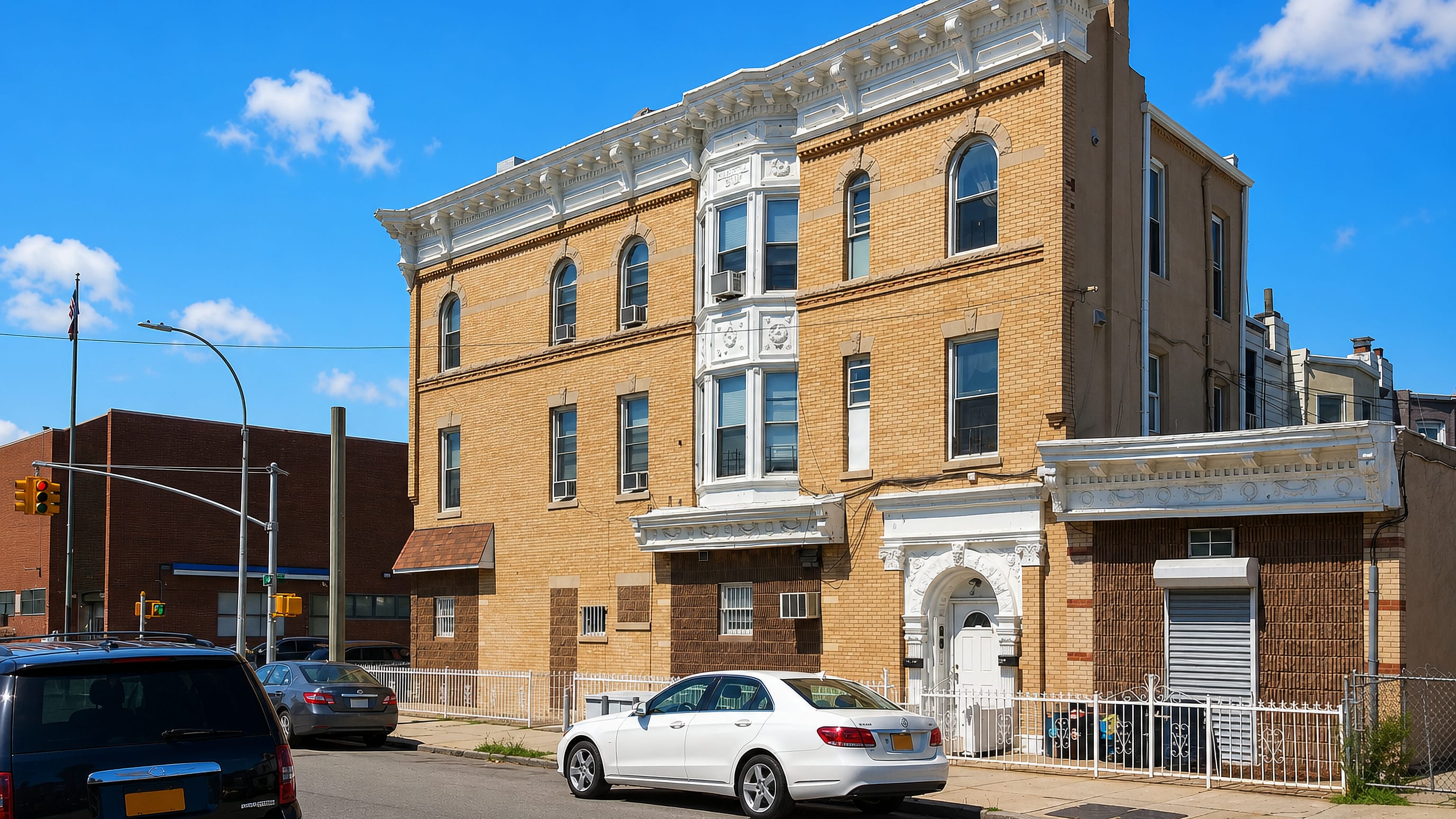 Sunlit three-storey brick and limestone corner building on a residential street in Bensonhurst, Brooklyn, New York City.