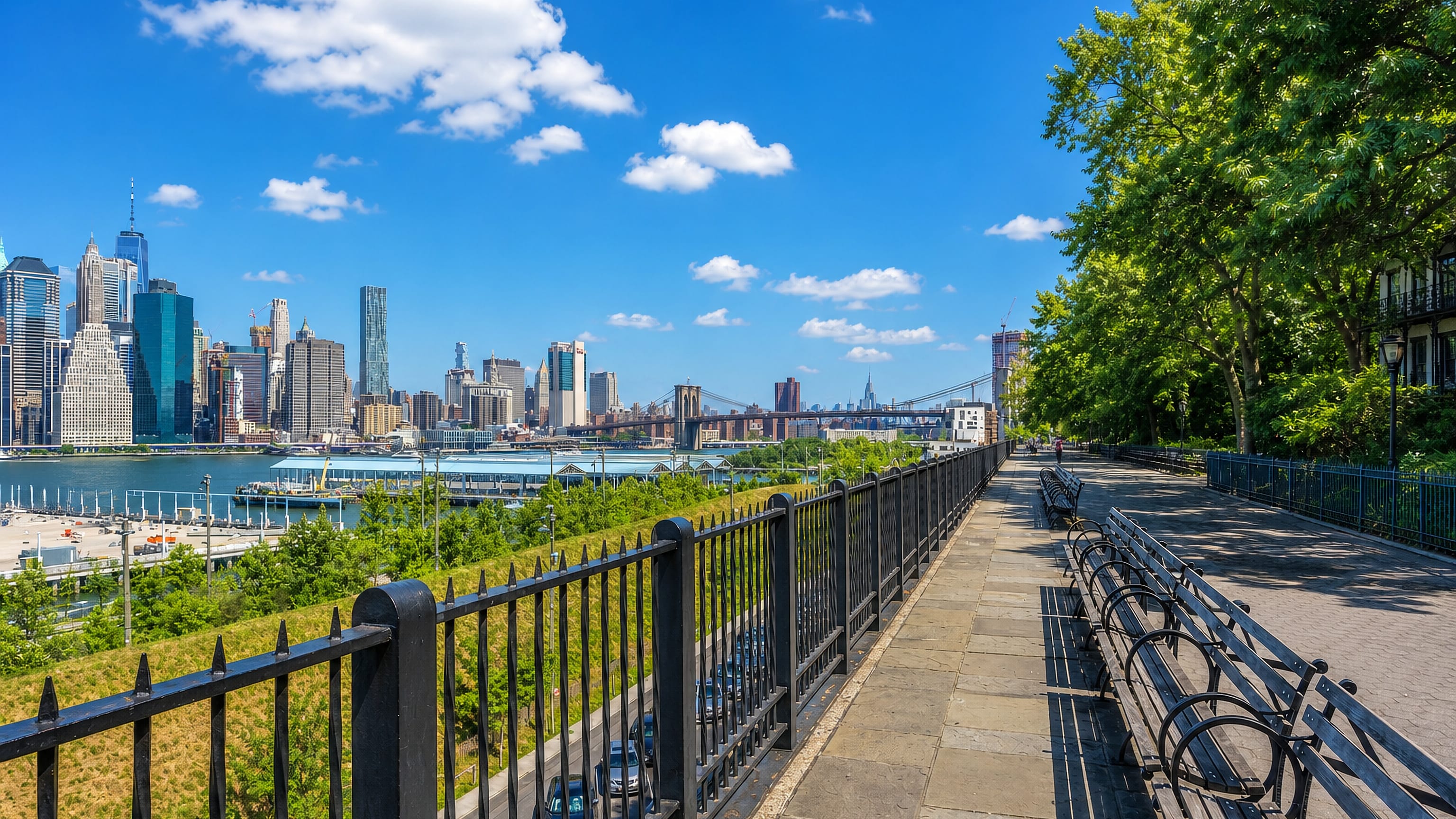 The Brooklyn Heights Promenade in New York, with benches facing the Lower Manhattan skyline and Brooklyn Bridge.